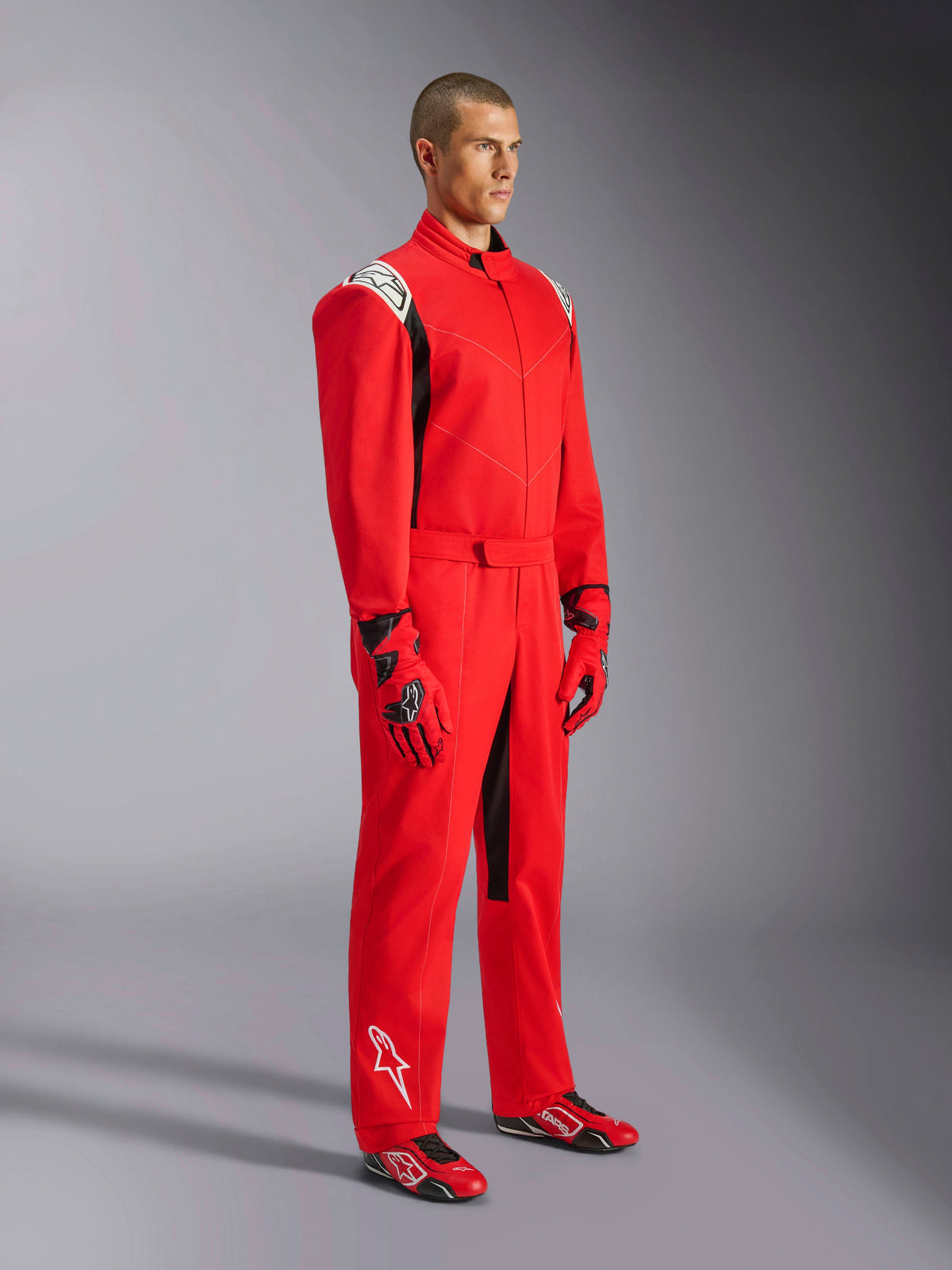 Alpinestars Kart Indoor V2 Suit, Red Karting Suit, worn by a model with matching red and black gloves and shoes, featuring white logos on shoulders and lower leg, black accents, designed for recreational karting and indoor tracks