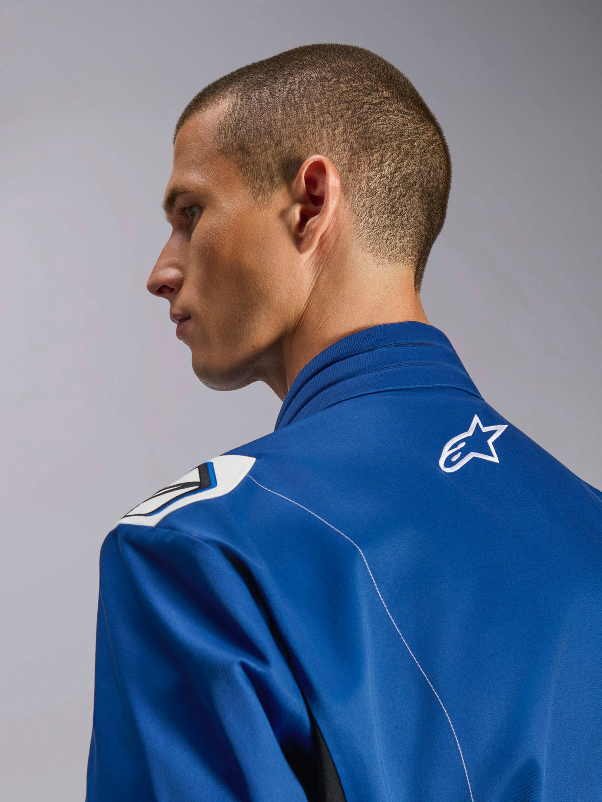 Alpinestars Kart Indoor V2 Suit, Blue karting suit, close-up side profile of the ergonomic collar and upper back with white star logo, featuring Formula 1-inspired shoulder design and durable poly-cotton twill construction