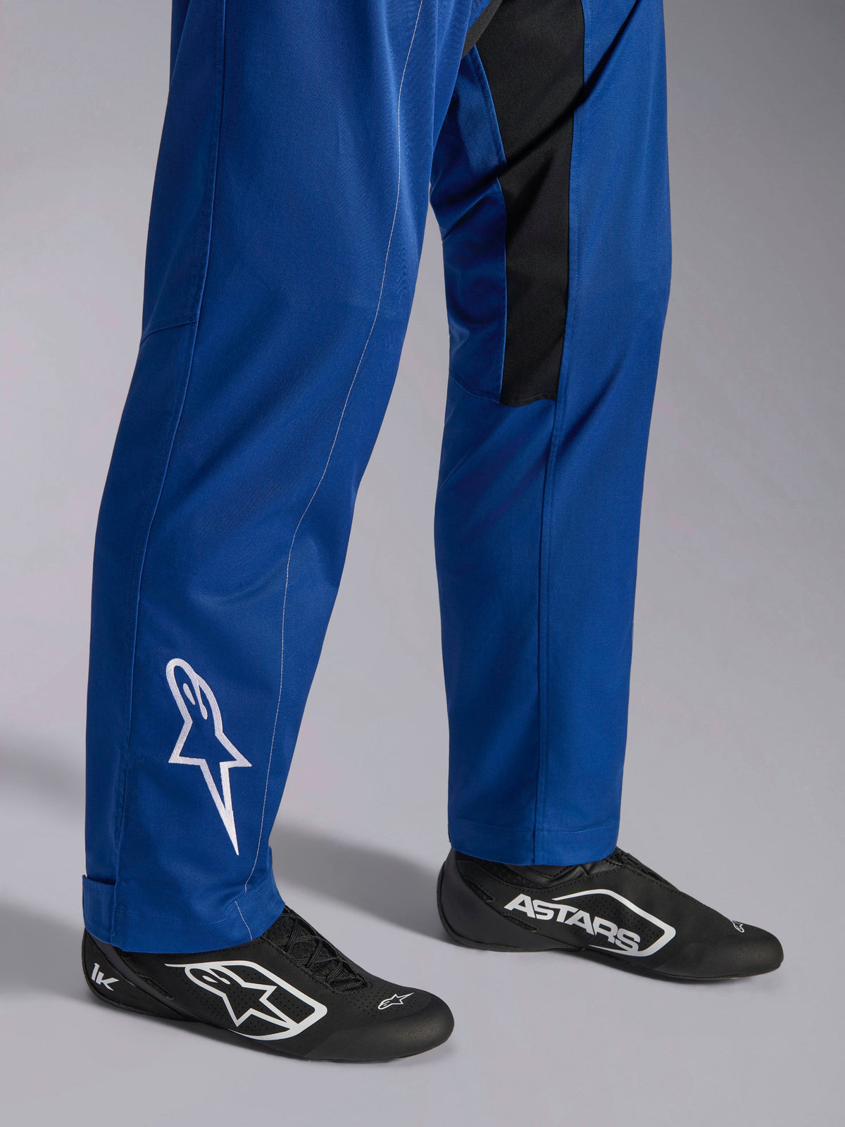 Alpinestars Kart Indoor V2 Suit, Blue, close-up of lower legs and feet showing white star logo on the ankle, adjustable leg bottoms, and black racing shoes, durable karting apparel for recreational track use
