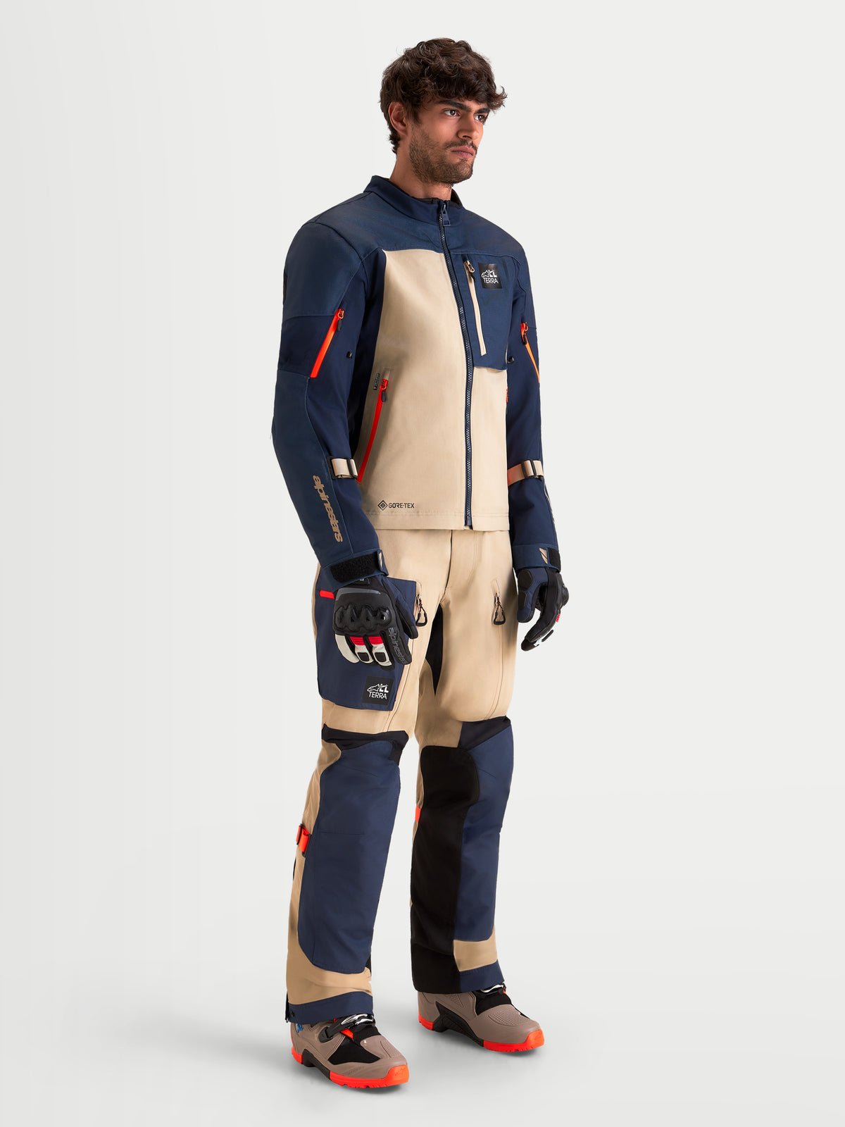 Alpinestars Arenis Gore-Tex Gear Set, conjunto de chaqueta y pantalones de moto para aventura de hombre en azul marino y aluminio, vista de cuerpo entero en un modelo que viste equipo de protección y botas a juego