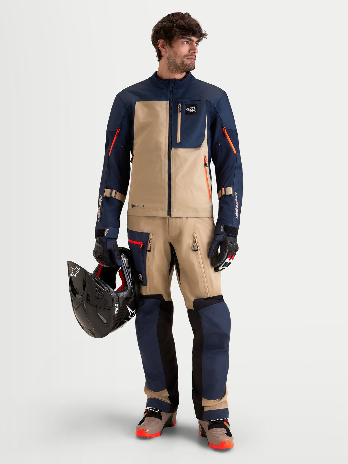 Alpinestars Arenis Gore-Tex Gear Set, conjunto de equipamiento de moto de aventura para hombre en azul marino y beige, vista frontal completa en un modelo con equipamiento a juego y un casco, con certificación AA de conducción todoterreno impermeable
