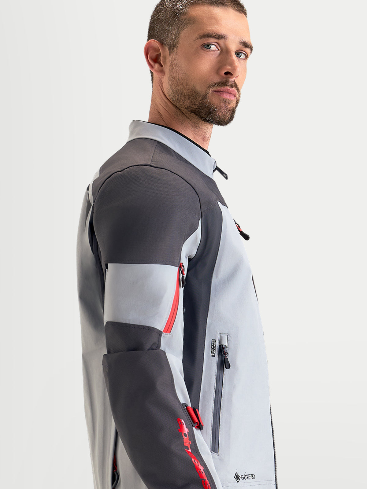 Alpinestars Arenis Gore-Tex Chaqueta, chaqueta de moto de aventura para hombre en gris medio, gris oscuro y negro, vista de perfil lateral que muestra la construcción textil impermeable y el cuello ergonómico
