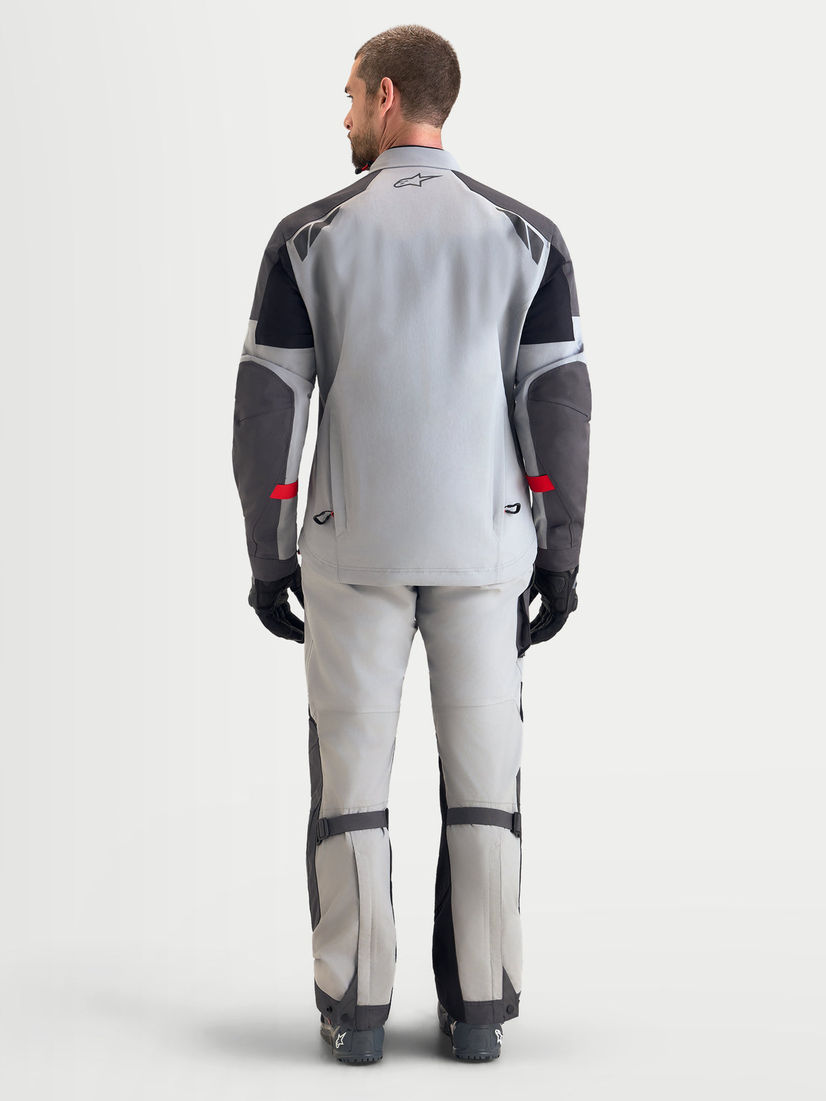 Alpinestars Arenis Gore-Tex Gear Set, men's adventure touring motorcycle jacket and pants in light gray and dark gray, rear profile view on a model showing waterproof GORE-TEX textile construction and ergonomic fit.