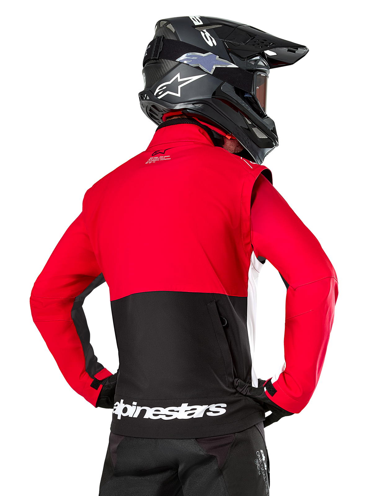 Chaqueta Alpinestars Pro-Dura, chaqueta de enduro off-road, roja y negra con logotipo de Alpinestars en blanco en el dobladillo trasero, vista desde atrás de un piloto con casco de motocross negro, diseño inspirado en el rally para conducción agresiva en senderos