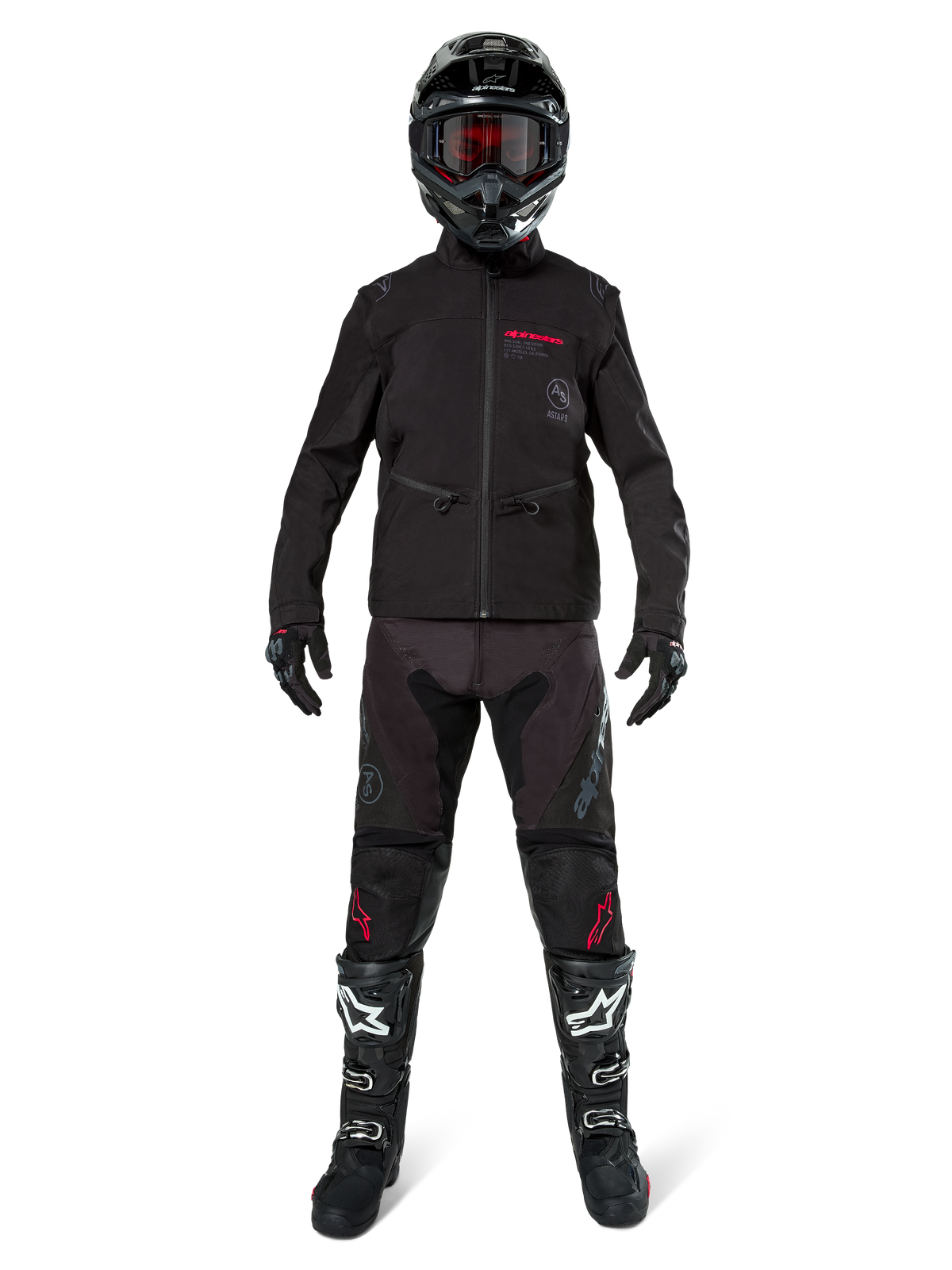 Piloto de motocross con la chaqueta Alpinestars Lite-Dura Softshell en negro con detalles rojos del logo, combinada con pantalones off-road negros a juego, casco negro y botas blancas y negras, equipamiento profesional completo de carreras de enduro.