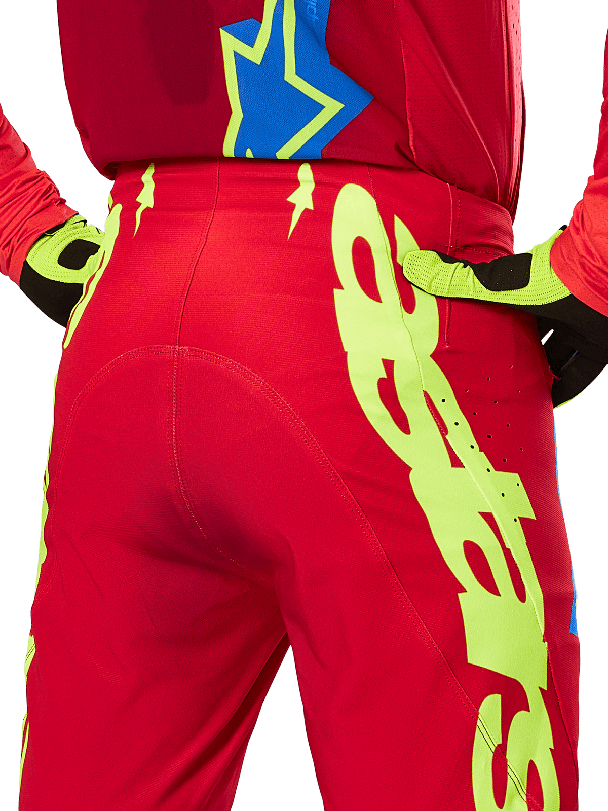 Pantalones Alpinestars Supertech Maker 2025, pantalones de motocross, rojo brillante y amarillo flúor, vista trasera con grandes gráficos amarillos en las piernas y guantes a juego en amarillo flúor y negro, equipamiento profesional de carreras todoterreno