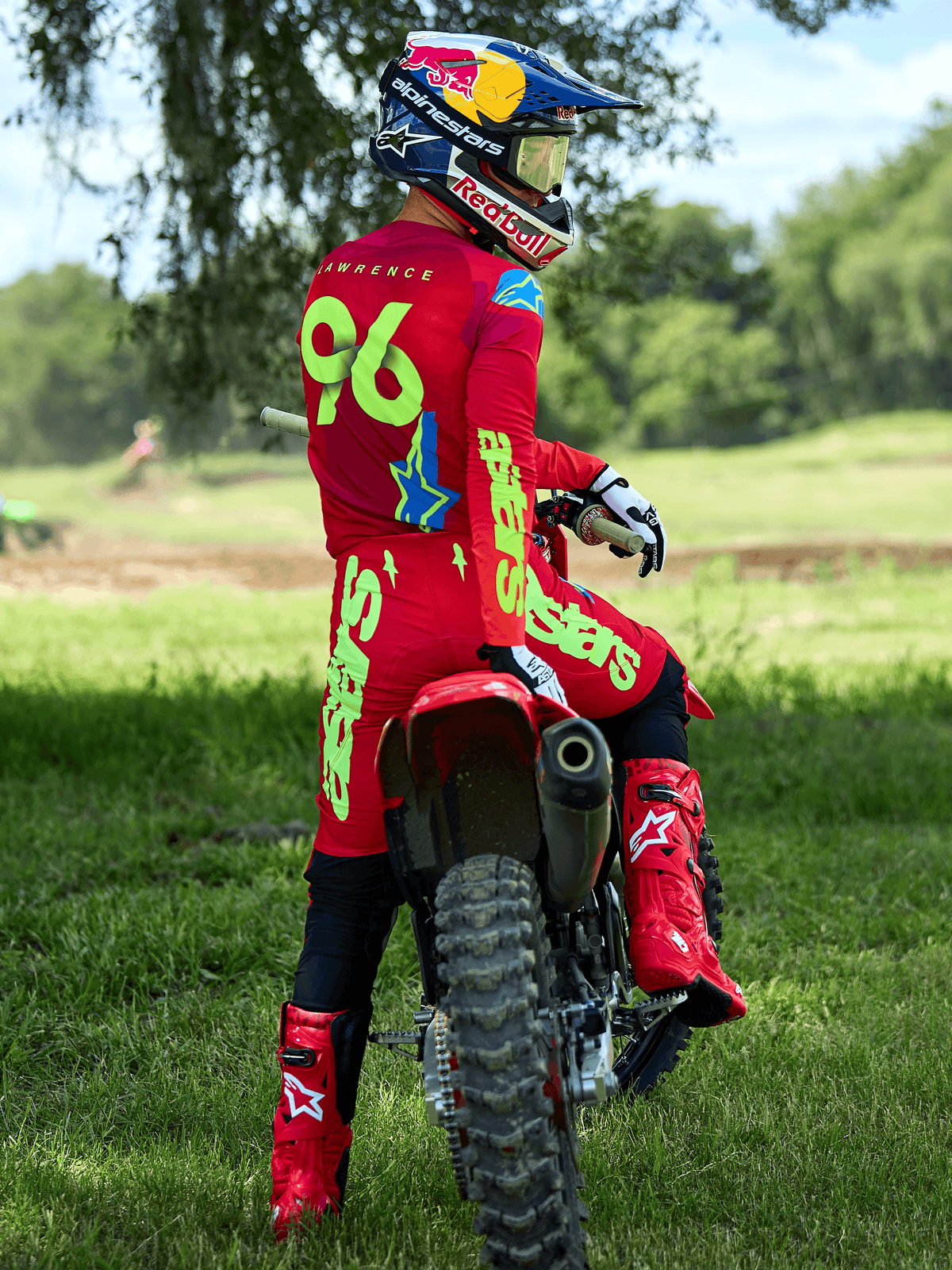 Piloto de motocross con el conjunto Alpinestars Supertech Maker 2025 en rojo brillante y amarillo flúor, sentado en una moto de cross roja, con el dorsal 96 en el jersey, botas y casco rojos a juego, equipamiento de carreras profesional para rendimiento off-road