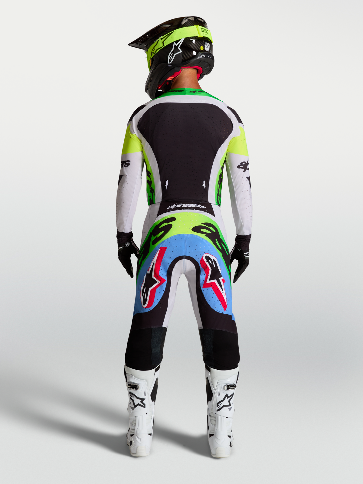Pantalones Supertech Dyna de Alpinestars, lila claro y verde flúor, vista trasera de piloto con equipo de motocross completo