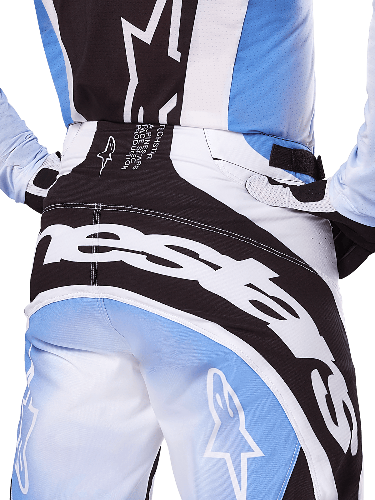 Alpinestars Techstar Melt Pants 2025, pantalones de motocross, color negro, blanco y azul, vista trasera de primer plano con logotipo blanco llamativo en el asiento, combinado con jersey y guantes Techstar Melt a juego, equipamiento profesional para motocross
