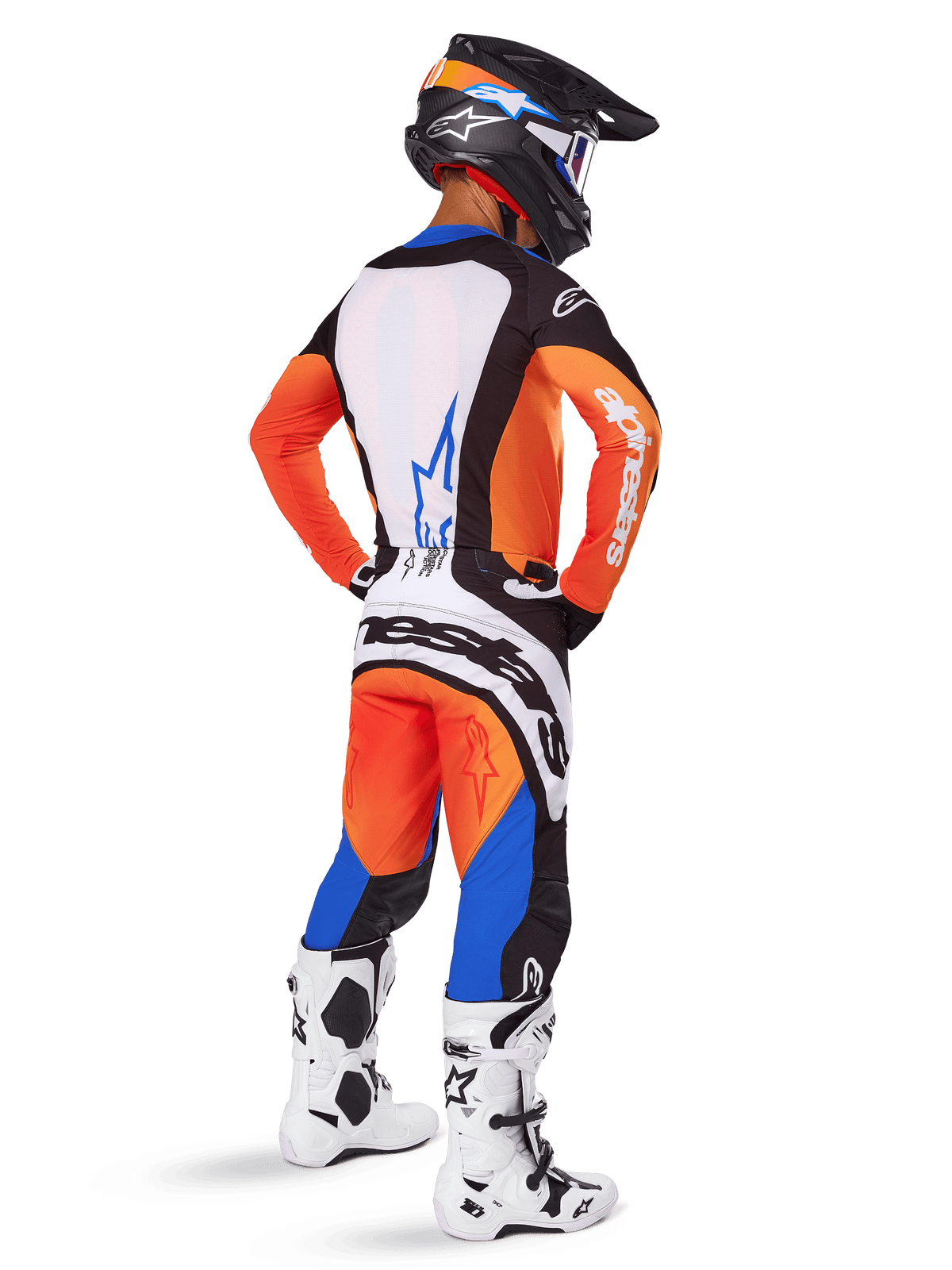 Piloto de motocross visto desde atrás con el conjunto Alpinestars 2025 Techstar Melt, jersey naranja y azul con panel trasero blanco y pantalones a juego, con logotipo blanco de gran tamaño, casco de motocross negro y botas de competición blancas.