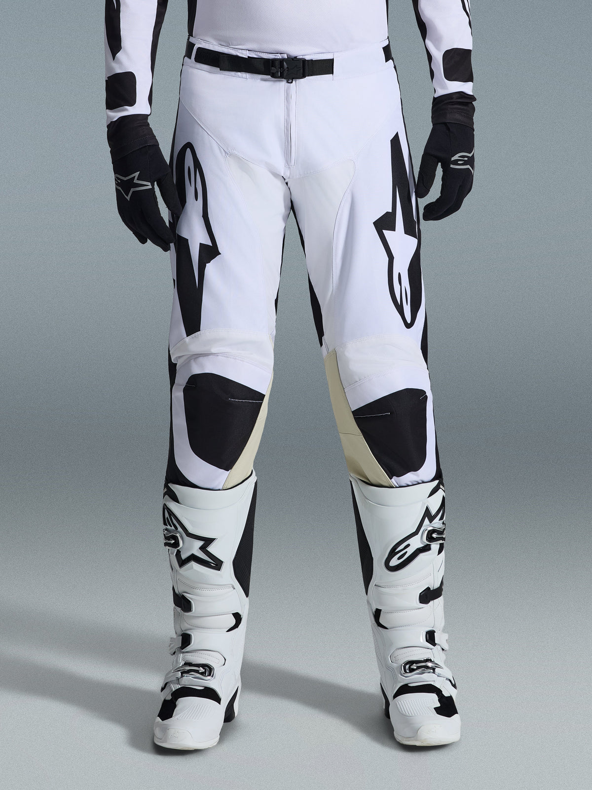 Alpinestars 2026 Racer Riway Pants, pantalones de motocross, blanco y negro, combinados con botas de motocross blancas y negras a juego y guantes negros, con el logotipo de Alpinestars en negro en los muslos, diseño técnico para rendimiento off-road.