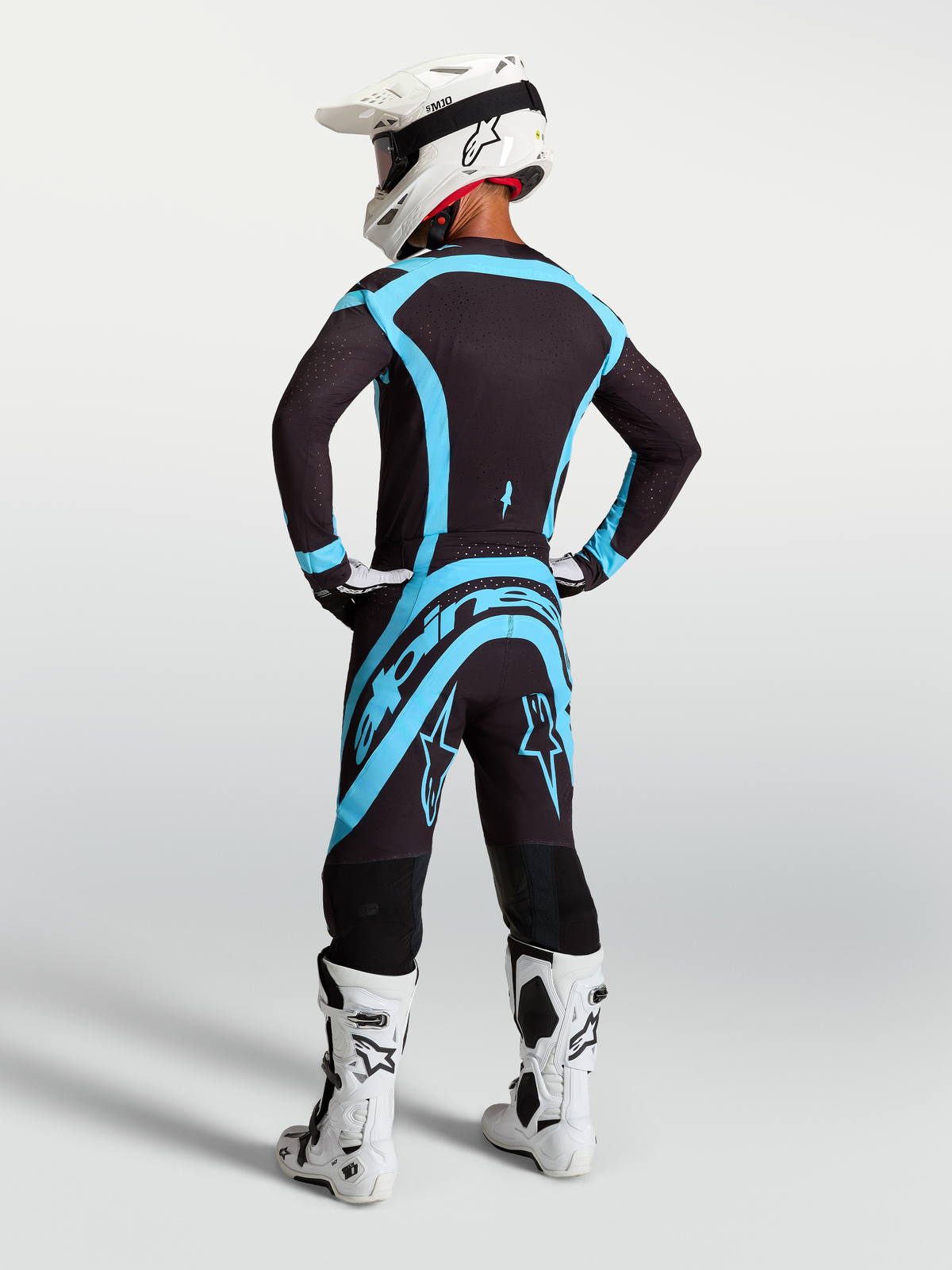 Pantalones Alpinestars Supertech Vesta, equipo de motocross profesional para hombre, negros y turquesa, vista trasera en modelo.