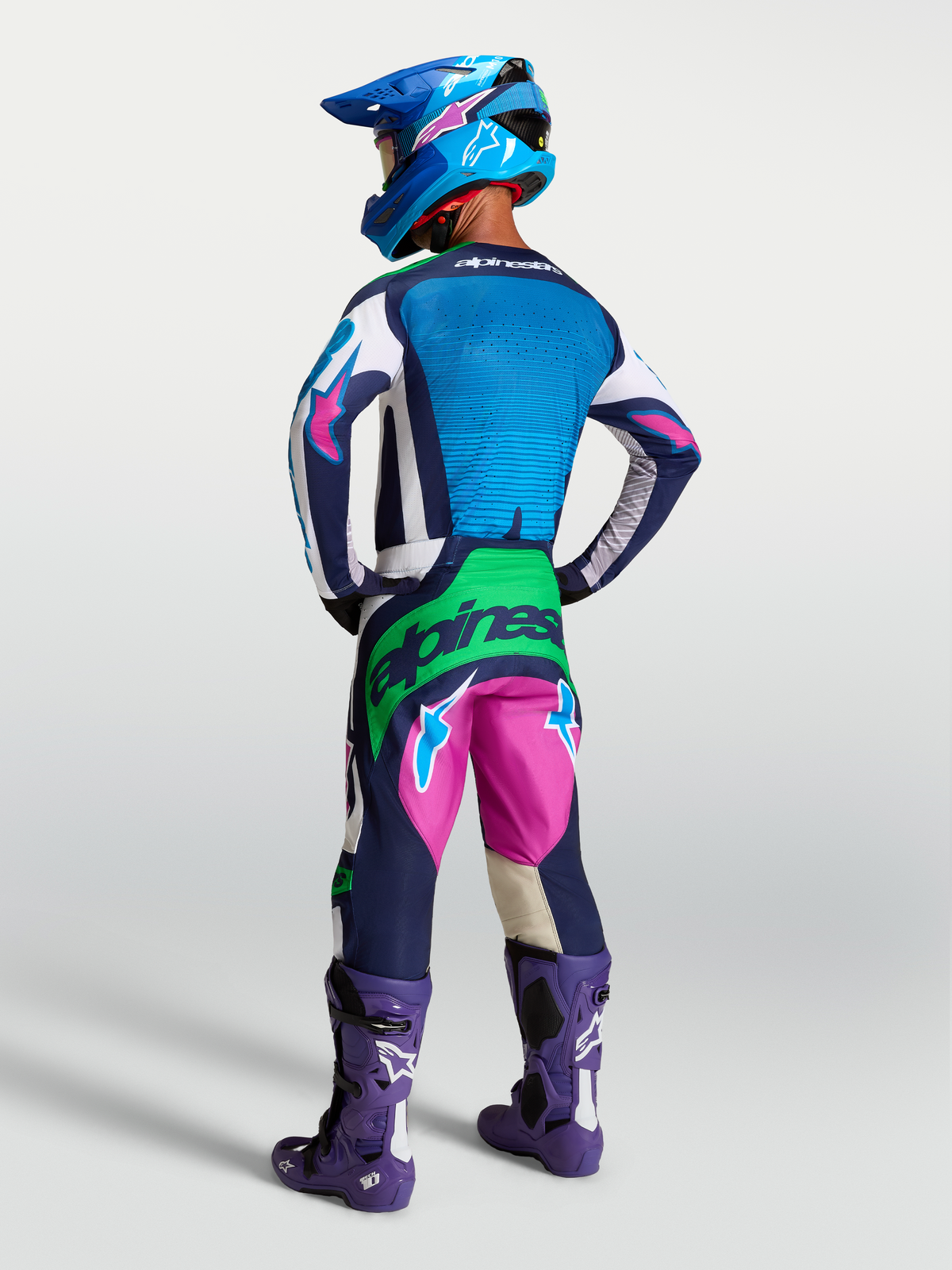 Techstar Maven Gear Set de Alpinestars, conjunto de motocross azul y rosa con detalles verde flúor, vista posterior en modelo