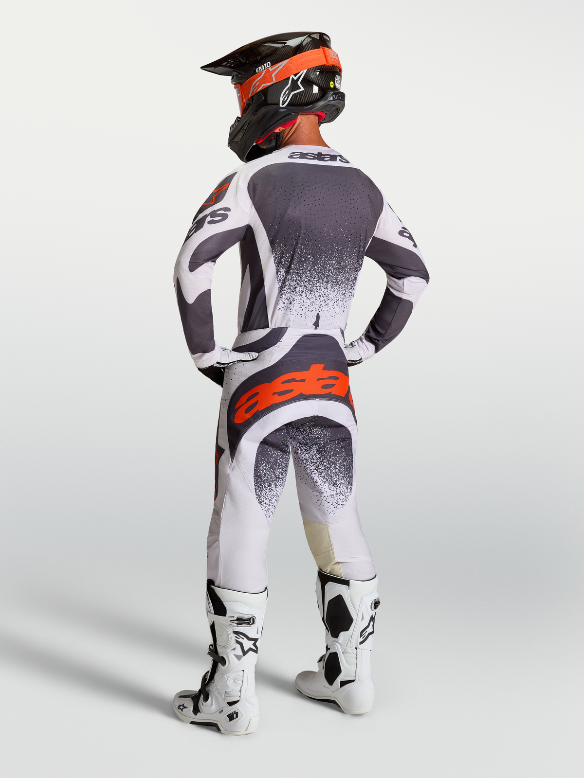Alpinestars Techstar Swan, jersey y pantalones de motocross de hombre, gris y blanco con rojo flúor, vista trasera en modelo