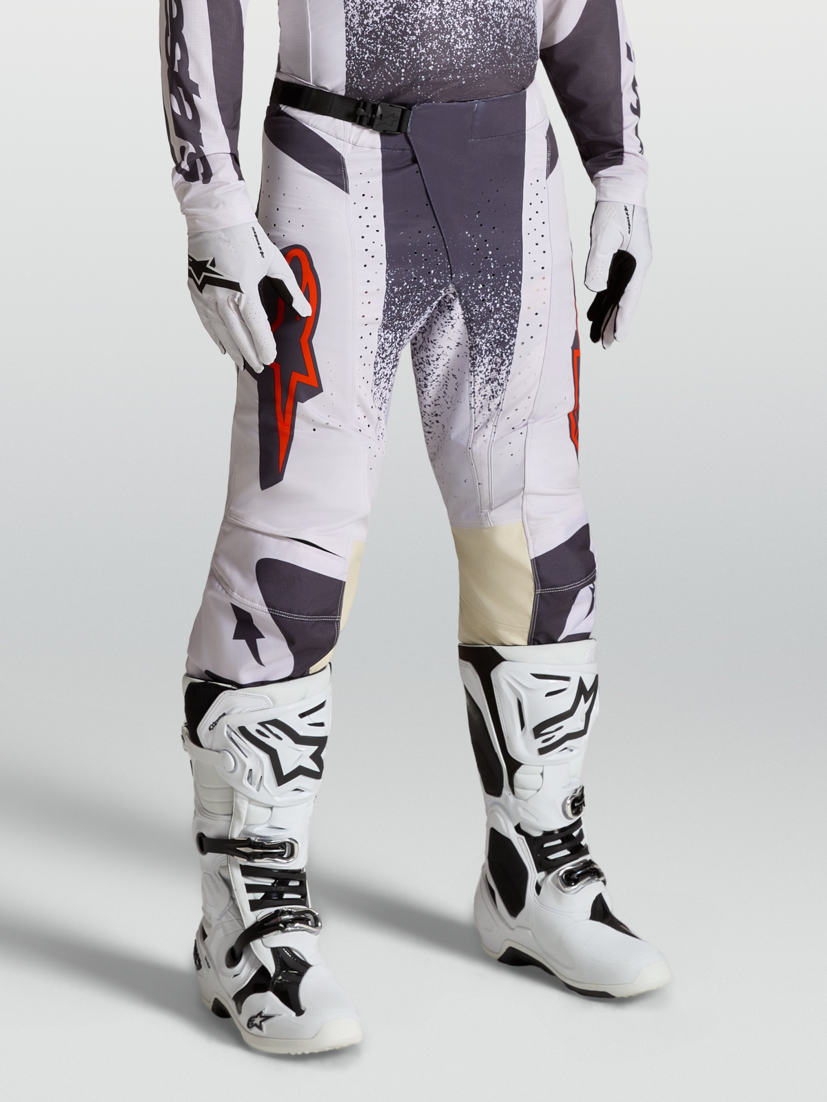 Alpinestars Pantalones Techstar Swan, pantalones de motocross para hombre, lila claro y gris oscuro con detalles en rojo flúor, conjunto con guantes y botas técnicas para competición todoterreno.