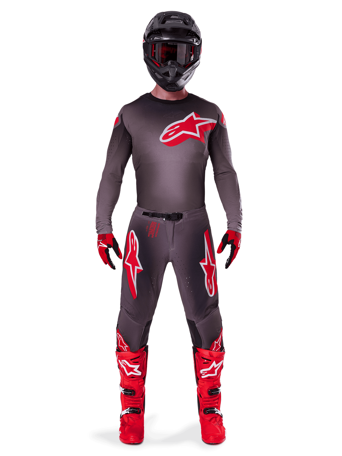 Piloto de motocross con equipamiento completo Alpinestars 2025 Supertech Lipan en Smoke Bright Red, con jersey y pantalones gris oscuro con logotipos rojos destacados, casco negro con gafas, guantes rojos y negros y botas de motocross rojas vibrantes, conjunto de carreras profesional coordinado