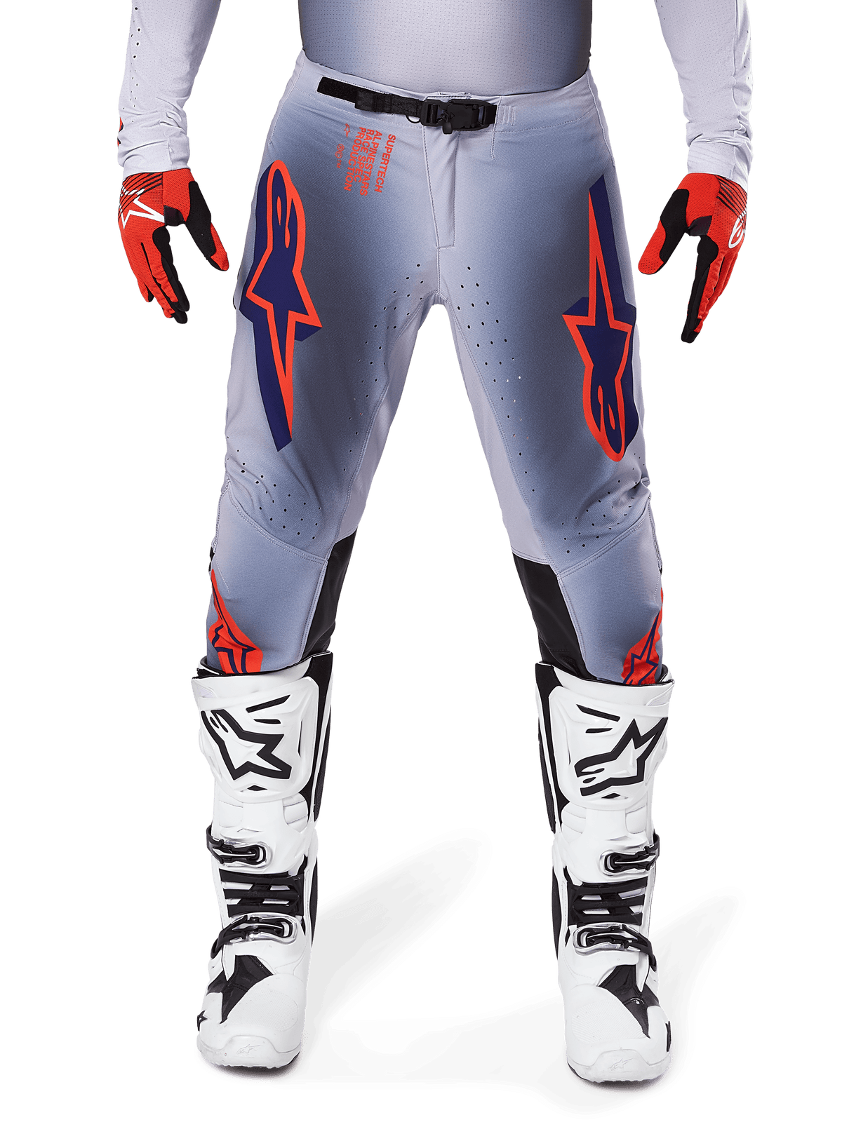 Pantalones Alpinestars Supertech Lipan 2025, pantalones de motocross, gris y naranja fluo, combinados con guantes rojos y negros y botas blancas y negras, con grandes logotipos de estrella de Alpinestars en los muslos y perforaciones de ventilación para carreras de nivel profesional.