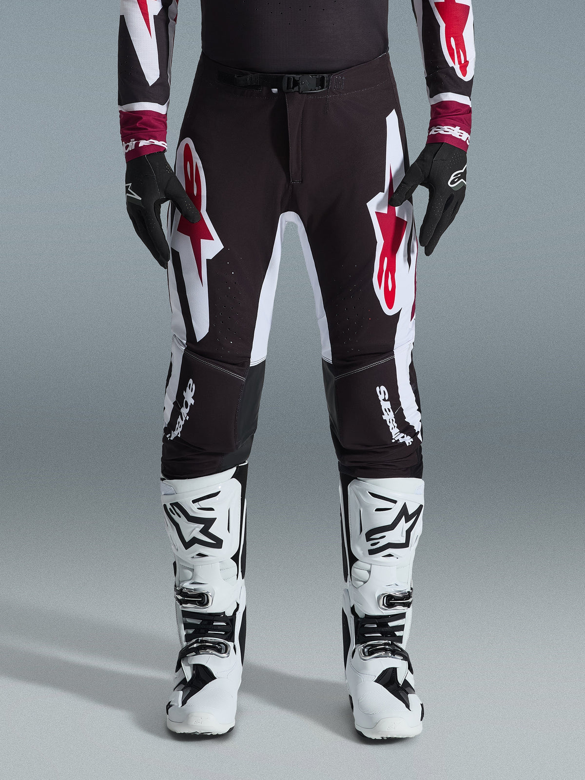 Alpinestars 2026 Supertech AFD Vista Pants, pantalones de motocross, negro, rojo y blanco, con logotipos gráficos grandes en los muslos y las rodillas, combinados con botas de carreras blancas y guantes negros, diseño atlético de competición para competiciones todoterreno de élite