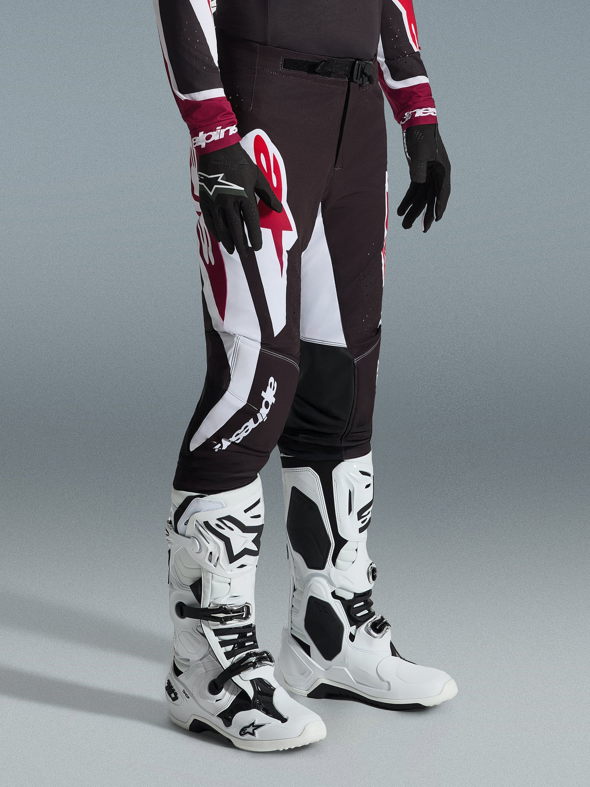 Pantalones Alpinestars Supertech AFD Vista 2026, pantalones de motocross en negro, rojo y blanco, usados con botas de motocross blancas y negras y guantes negros, con grandes patrones gráficos en blanco y rojo y diseño de ajuste atlético de competición