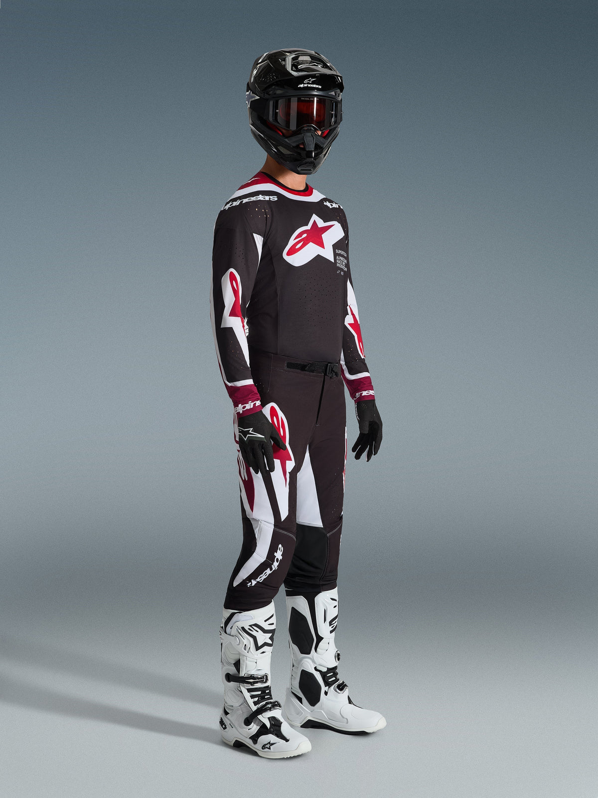 Alpinestars 2026 Supertech AFD Vista Pants, pantalones de motocross, negro, rojo y blanco, usados con jersey de carreras a juego, casco negro con gafas rojas, guantes negros y botas blancas, equipamiento de rendimiento atlético para carreras off-road