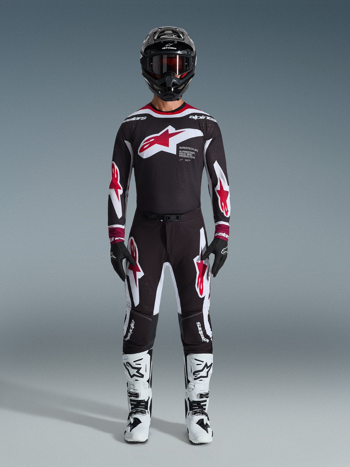 Pantalones Alpinestars Supertech AFD Vista 2026, pantalones de motocross, negro, rojo y blanco, usados como un conjunto completo de equipamiento de competición con jersey a juego, casco negro y botas blancas, con logotipos llamativos de Astars en rojo y blanco en el pecho y las piernas, diseñados para un rendimiento todoterreno de élite
