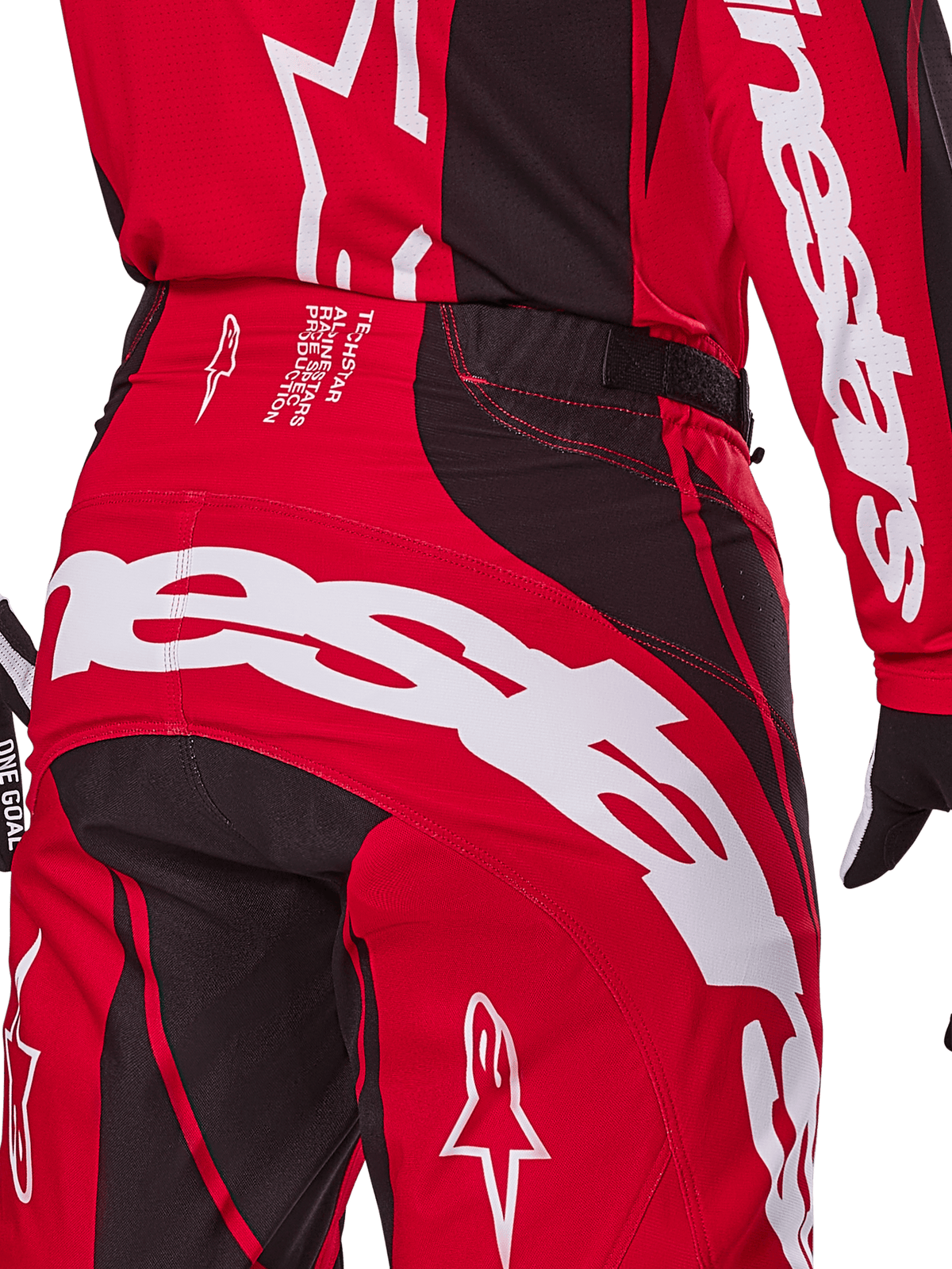 Alpinestars Techstar Dreem Pants 2025, pantalones de motocross en rojo brillante y negro, primer plano de la zona posterior de la cintura y el asiento con la marca Alpinestars en blanco llamativo, paneles elásticos negros y texto técnico de producción en la cintura, diseñados para el rendimiento en carreras todoterreno.