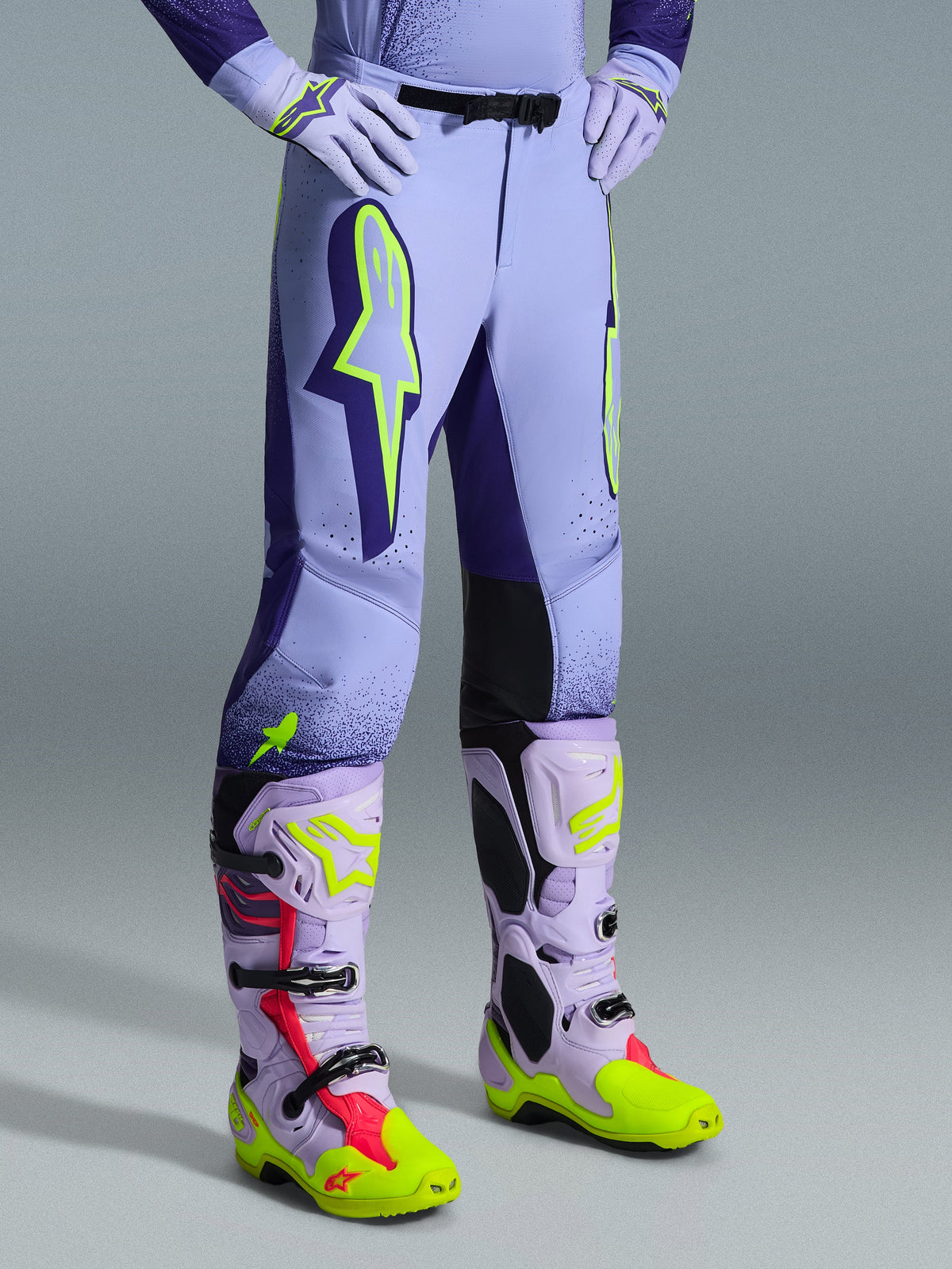 Alpinestars 2026 Supertech Scenz Pants, Motocross Pants, Purple and Yellow Fluo, worn with matching motocross boots and gloves, featuring large neon yellow logos, athletic fit, and laser-cut perforations for ventilation