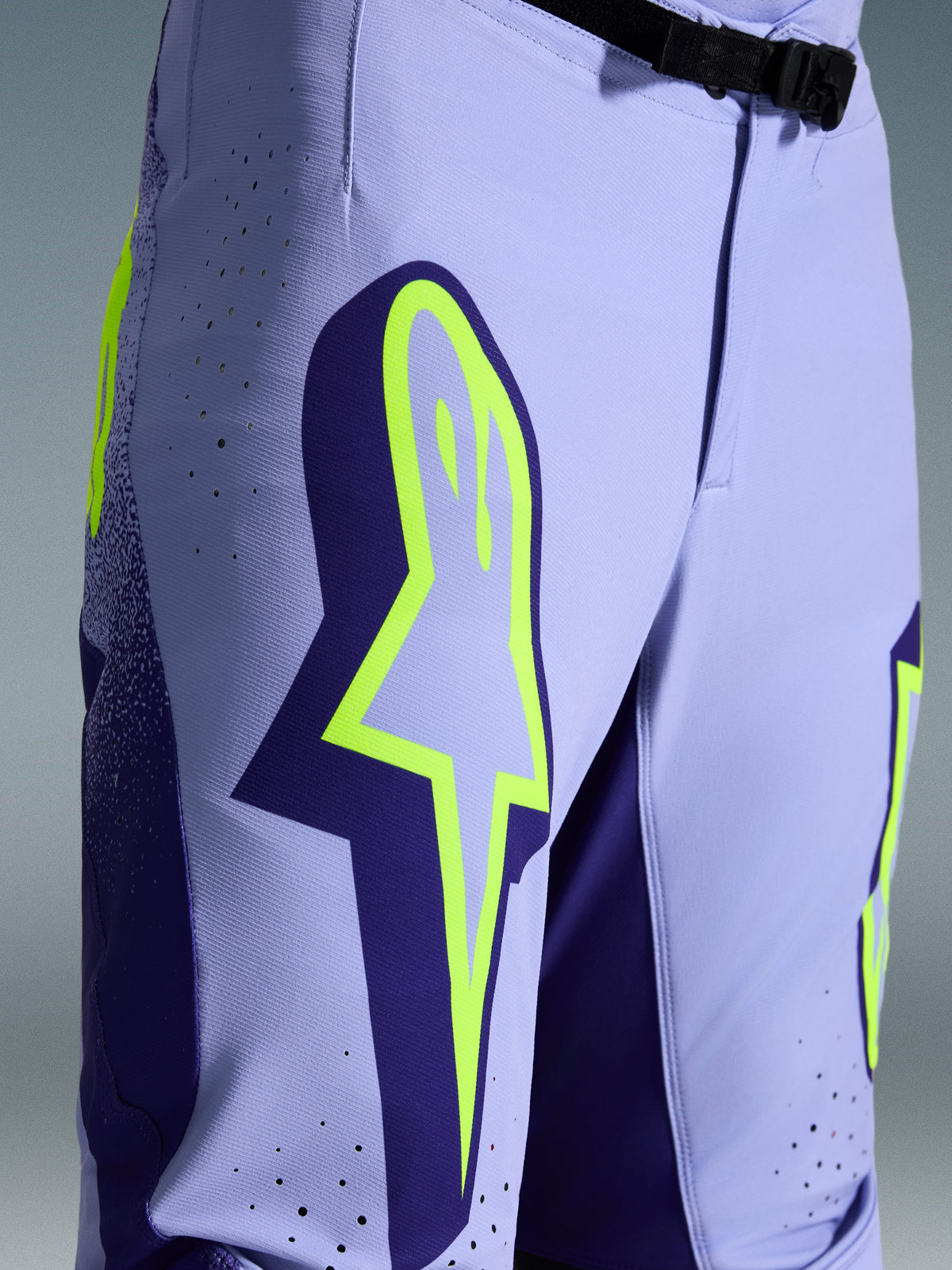 Alpinestars 2026 Supertech Scenz Pants, Motocross Pants, Purple Yellow Fluo, close-up featuring large yellow logo on the thigh, laser-cut perforations for ventilation, and magnetic waist buckle, athletic-fit off-road gear