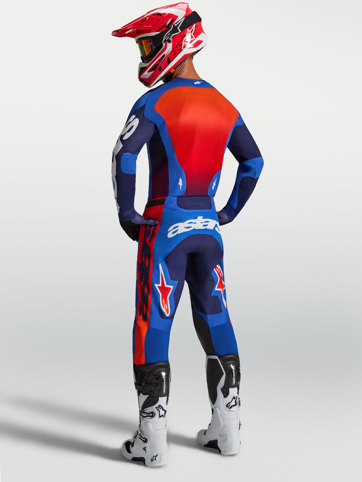 Alpinestars Racer Hunt, pantalones de motocross para hombre, azul y rojo, vista trasera con ajuste ergonómico precurvado.