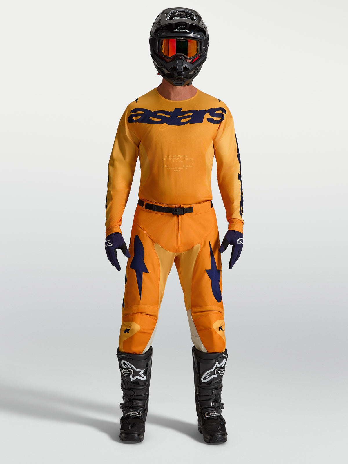Alpinestars 2027 Racer Amber, conjunto de motocross naranja y azul profundo con jersey, pantalones y botas.