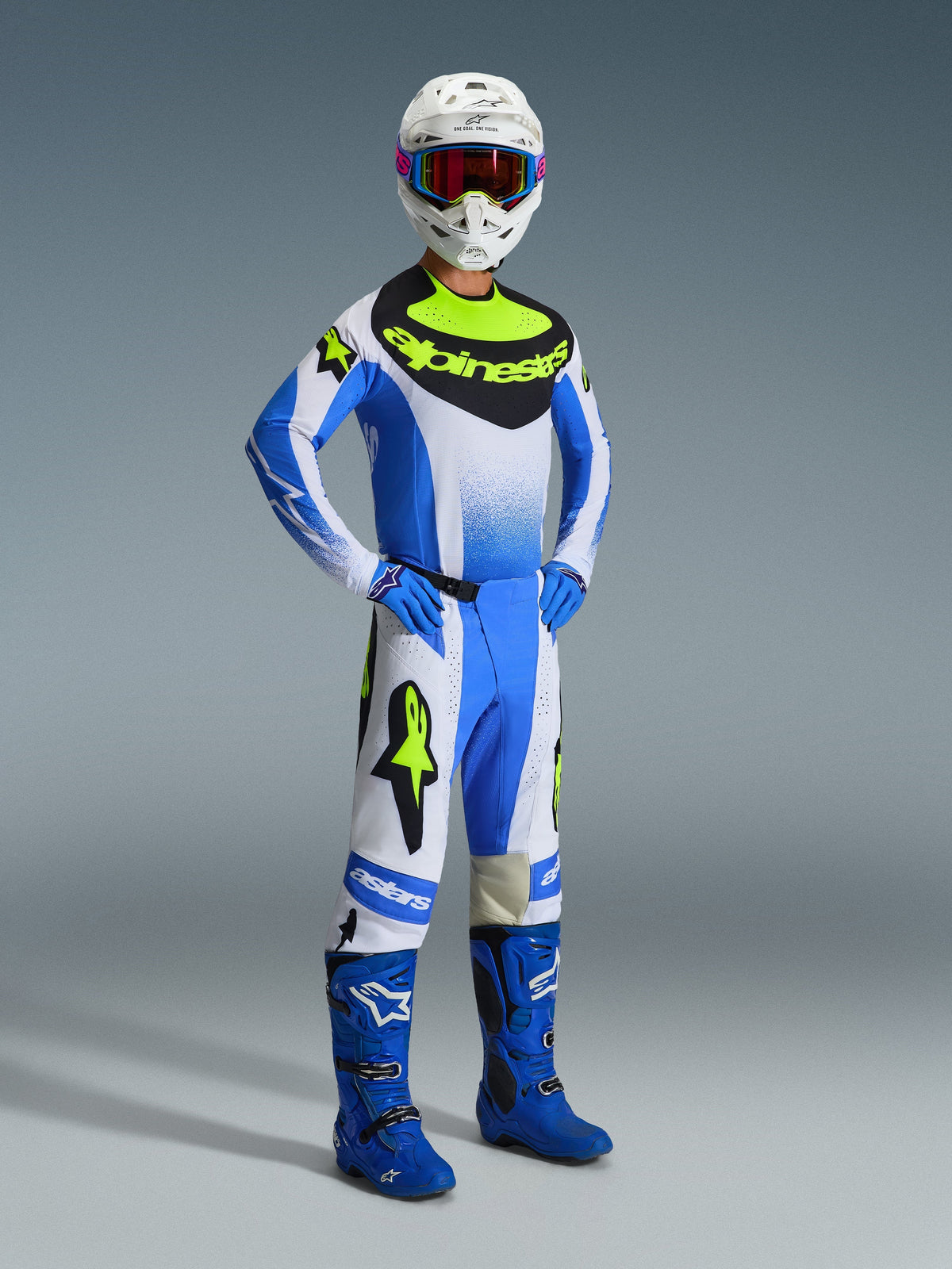 Piloto de motocross con pantalones Alpinestars 2026 Techstar Knif en Ucla Blue, negro y amarillo flúor, conjunto completo de equipo de carreras con jersey a juego y logotipo destacado de Alpinestars, botas azules, casco blanco con gafas y guantes azules, postura atlética para rendimiento todoterreno