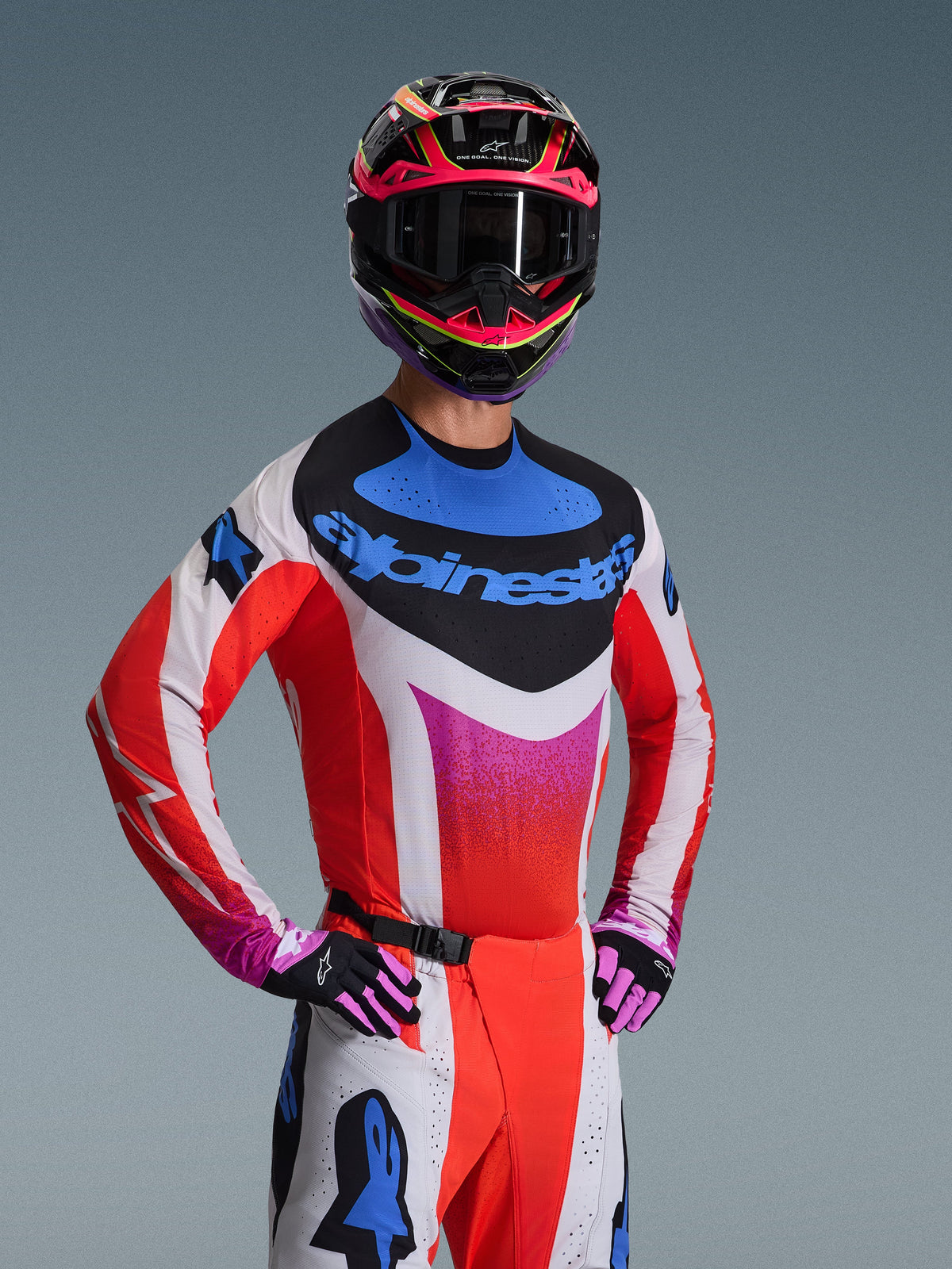 Alpinestars Techstar Knif Jersey 2026, jersey de motocross, blanco con patrones de degradado en rojo, azul y rosa, con un llamativo logotipo azul en el pecho, usado con casco y guantes a juego, diseño de competición atlético para rendimiento off-road