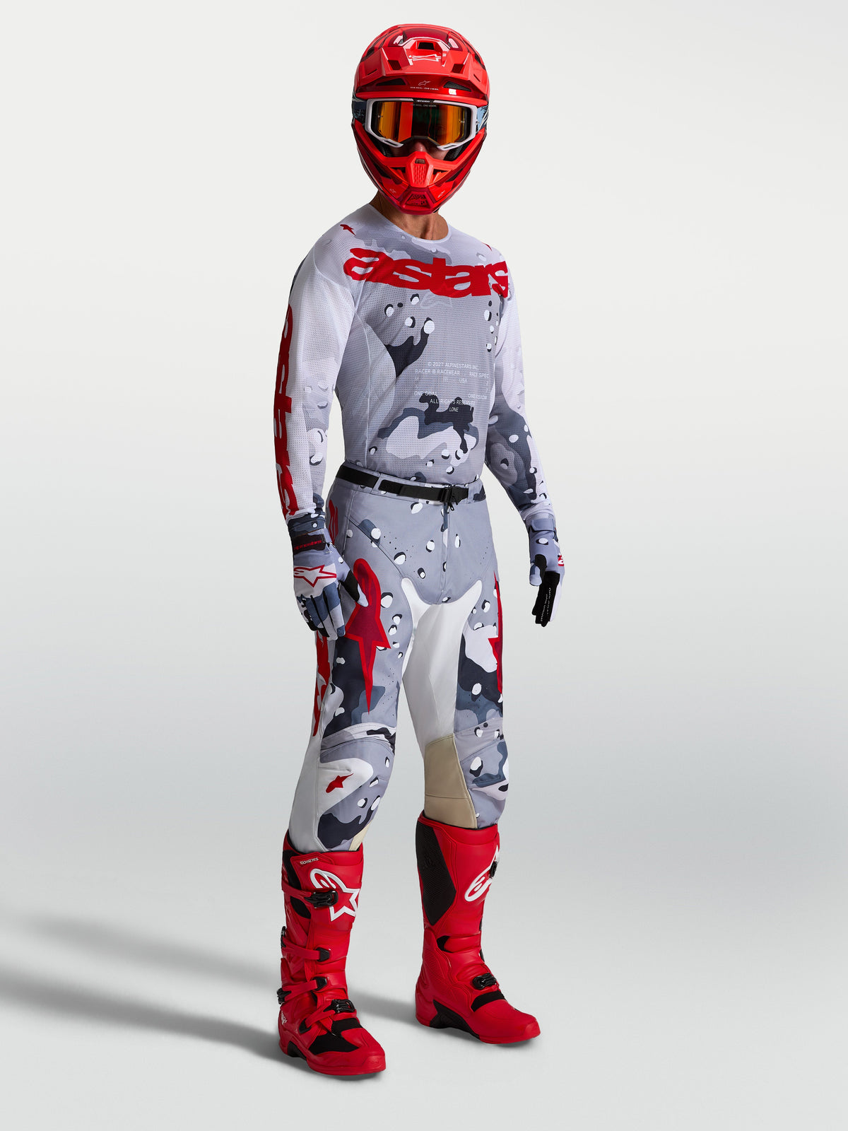 Alpinestars Racer Air Lone, pantalones y conjunto de motocross para hombre, camuflaje gris y rojo con jersey y botas rojas.