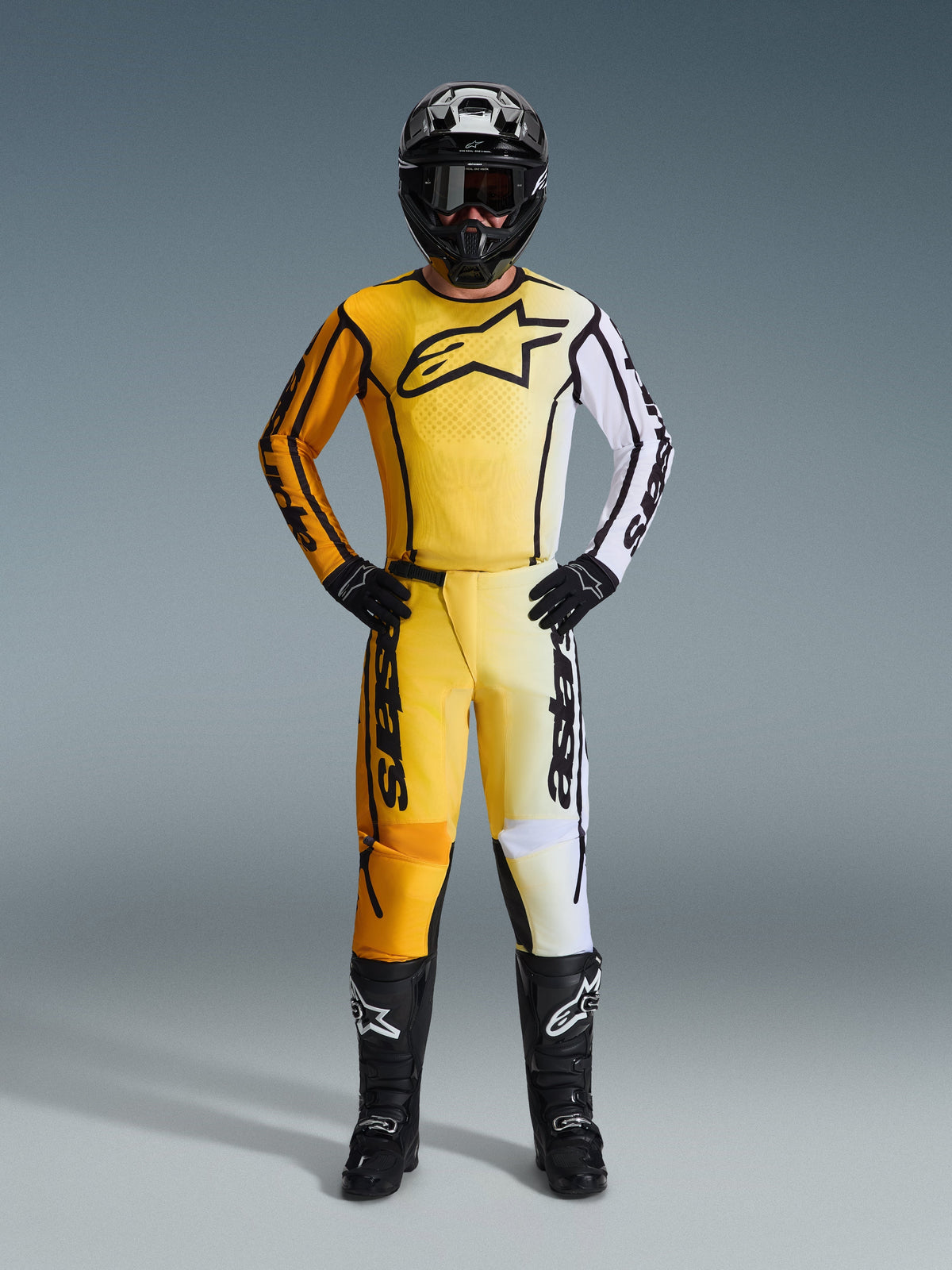 Alpinestars 2026 Fluid Apex Pants, pantalones de motocross en amarillo, negro y blanco, usados como un conjunto de carreras completo con jersey degradado a juego, casco negro y botas, equipamiento profesional para conducción off-road