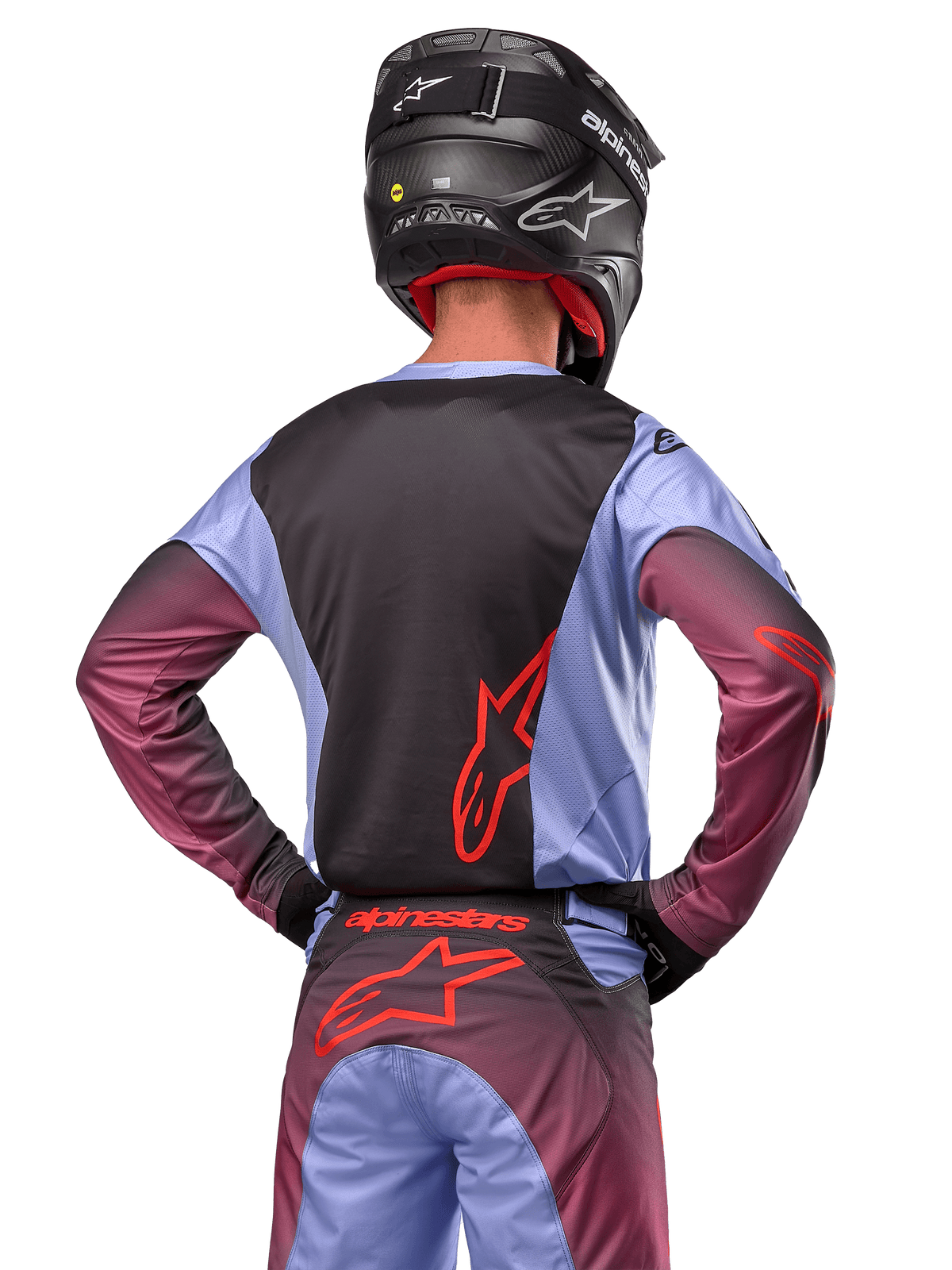 Piloto de motocross visto desde atrás con la equipación Alpinestars 2024 Racer Hoen, jersey en púrpura Lavan y negro con logotipo rojo, pantalones a juego con detalles rojos, casco negro, conjunto coordinado para carreras todoterreno