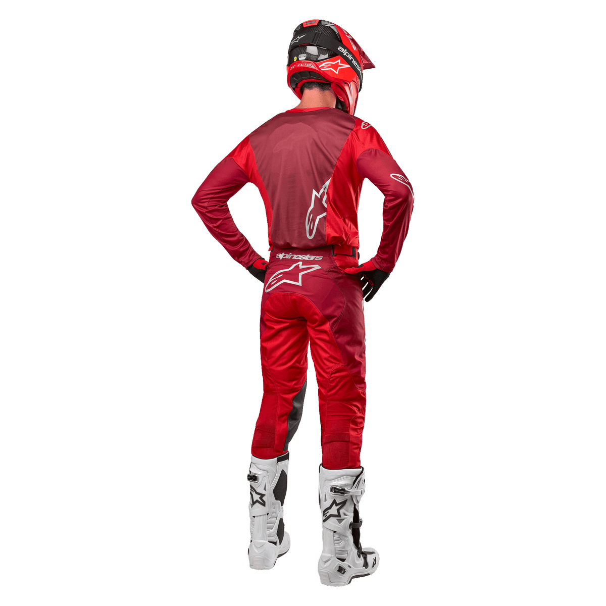 Pantalones Alpinestars Racer Hoen 2024 y jersey a juego en Mars Red Burgundy, vista trasera de un piloto de motocross con equipamiento completo que incluye casco rojo y botas blancas, destacando el ajuste atlético y la marca para carreras fuera de carretera