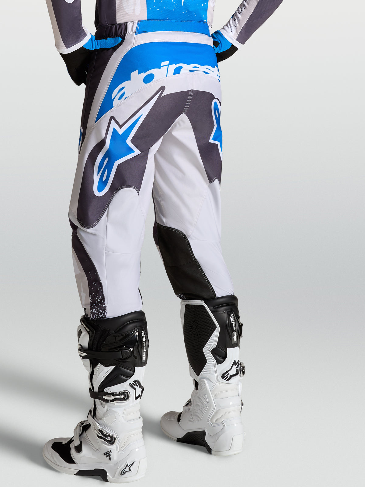 Pantalones Fluid Drag de Alpinestars, pantalones de motocross para hombre, gris y azul, vista trasera con patrón ergonómico 3D.