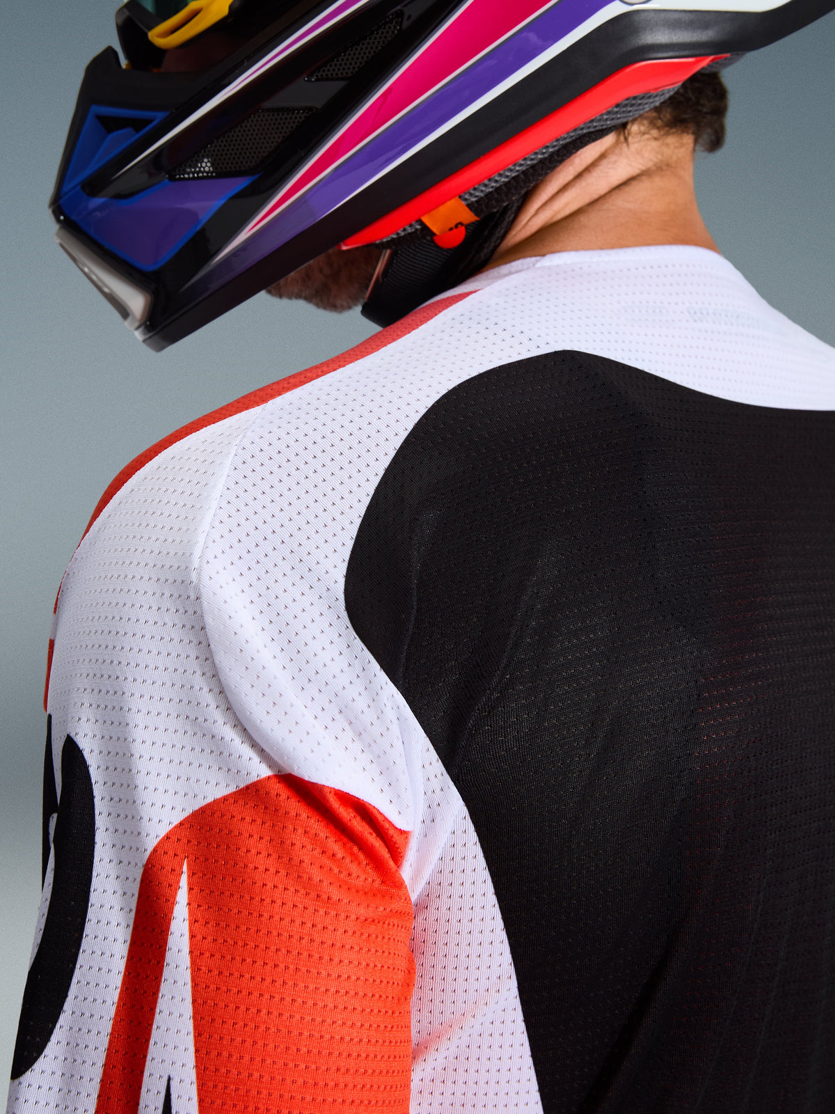 Alpinestars 2026 Racer Air Portl Jersey, jersey de motocross, multicolor con paneles blancos, negros y rojos, primer plano de la construcción de malla perforada en el hombro y la espalda para ventilación, usado con un casco de motocross colorido