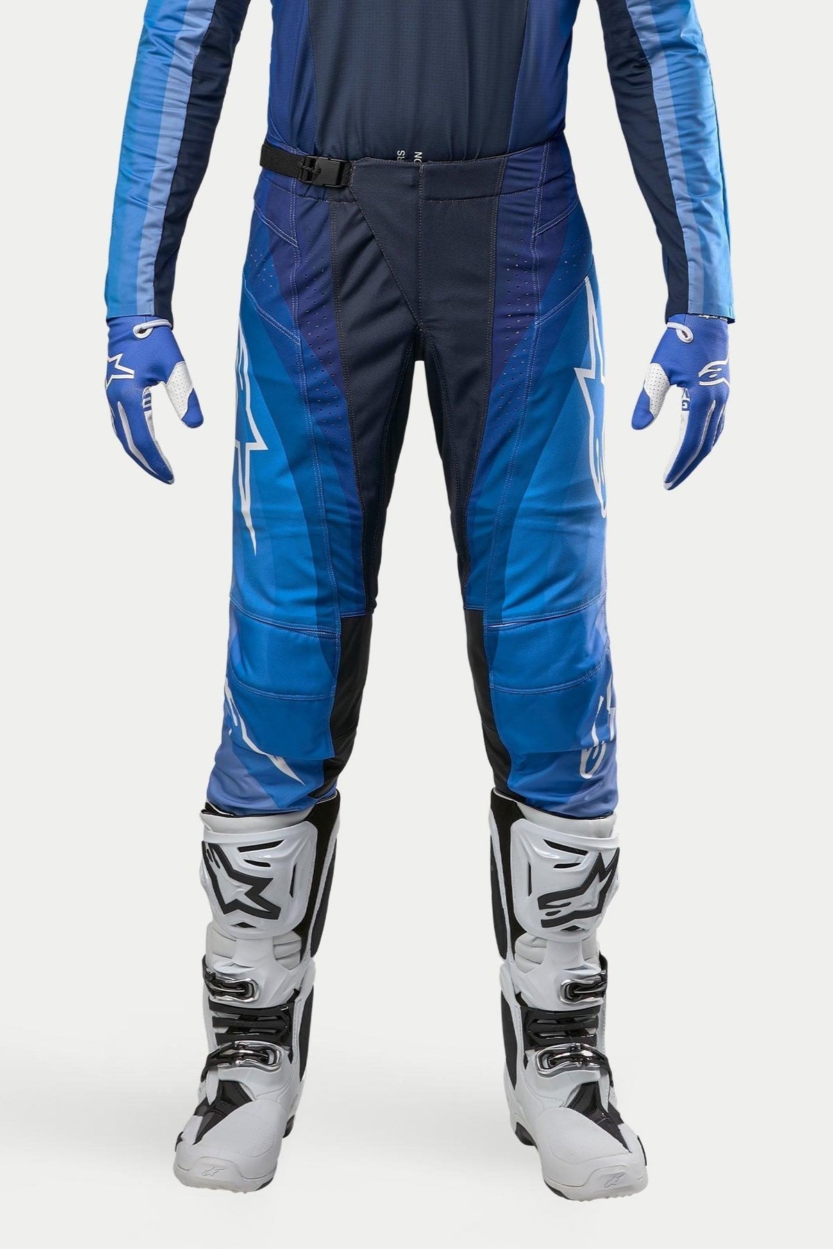 Pantalones Alpinestars 2024 Techstar Pneuma, pantalones de motocross, azul marino y azul claro, combinados con jersey azul a juego y botas blancas, con logotipos blancos de Alpinestars y cierre de hebilla magnética, diseñados para un rendimiento profesional off-road