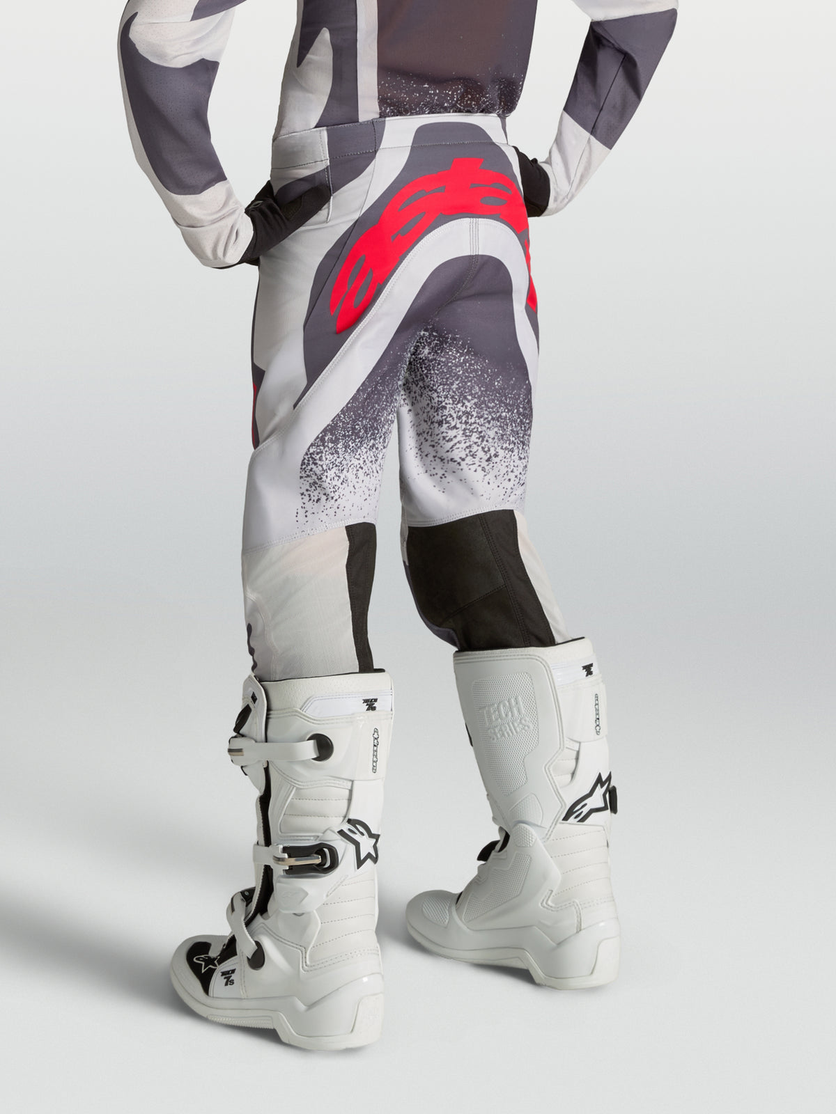 Pantalones Alpinestars Supertech Swan Juveniles, pantalones de motocross para jóvenes, grises y lila con logotipo rojo, vista trasera en modelo.