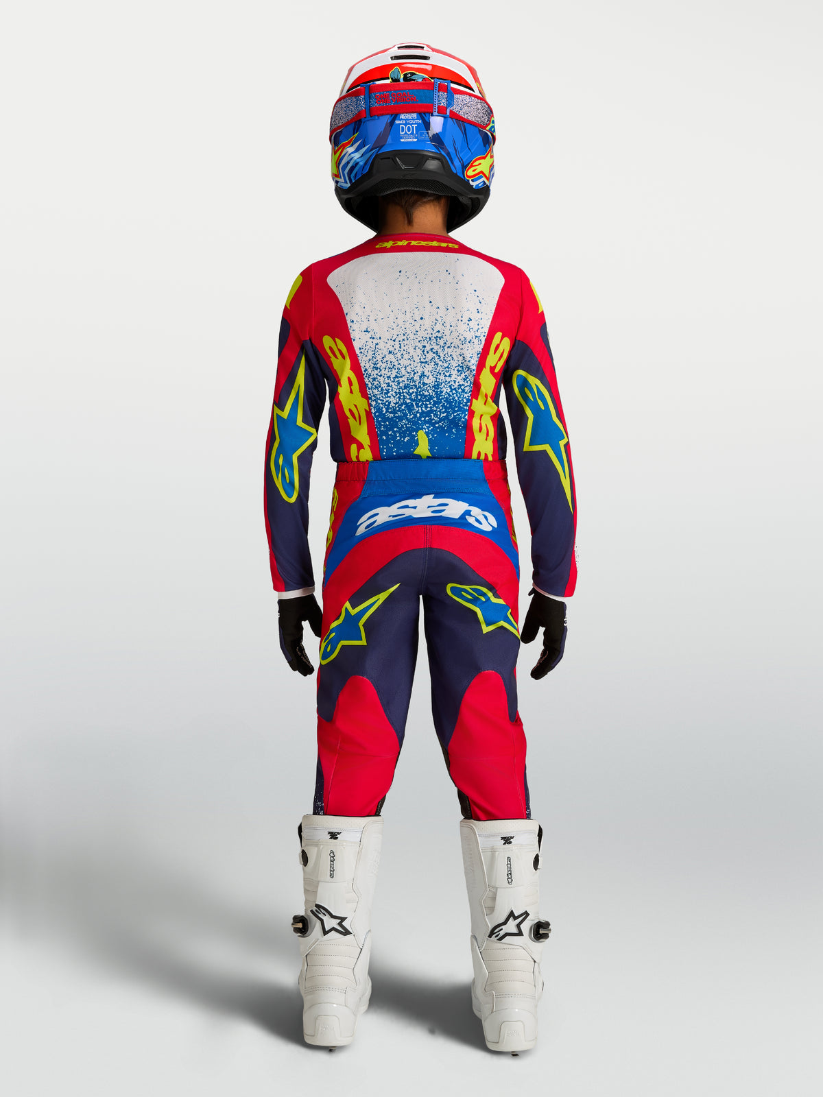 Alpinestars pantalones Fluid Drag Juvenil, kit de motocross azul y rojo, vista trasera con jersey y botas a juego.