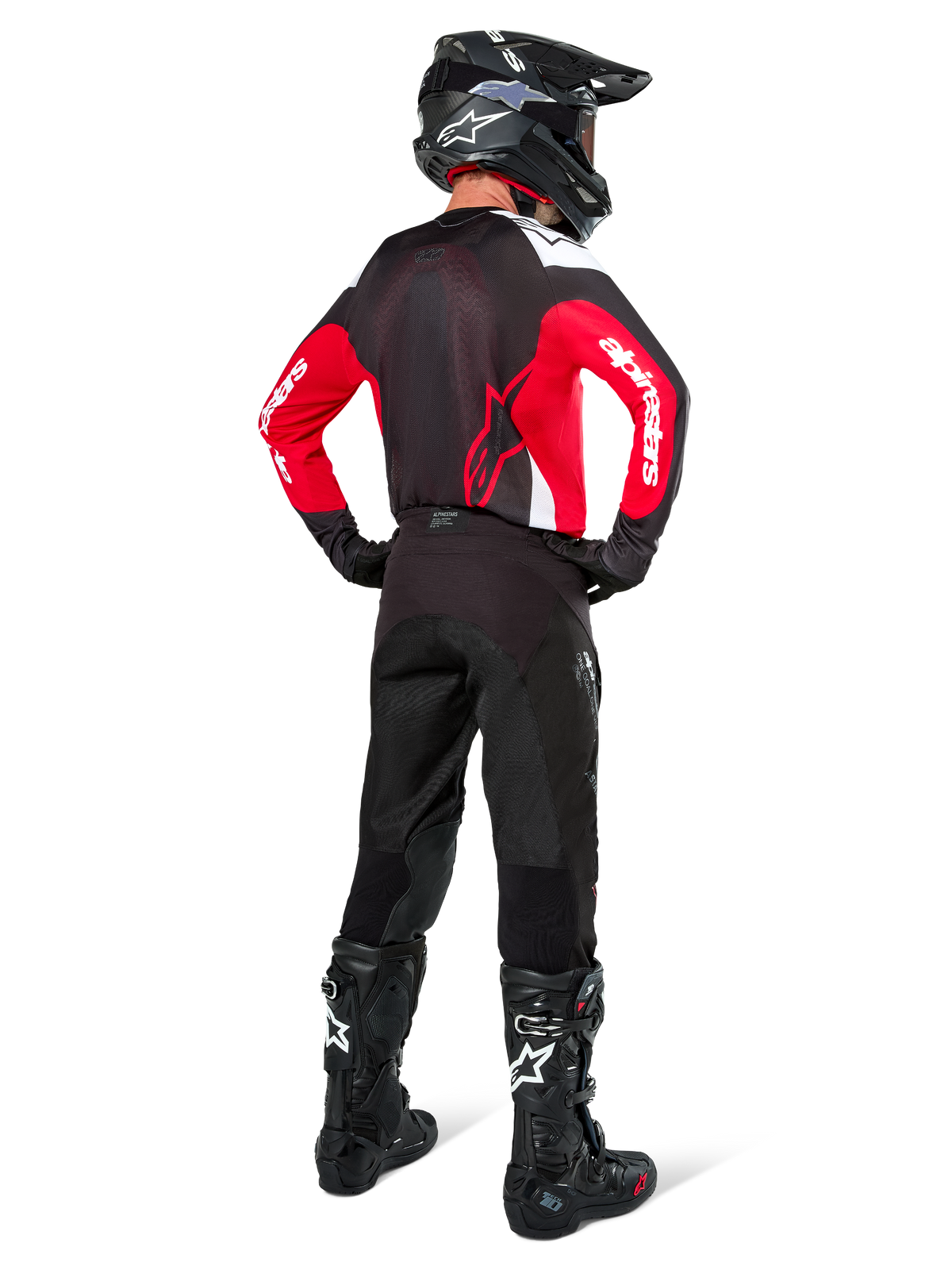 Piloto de motocross de espaldas con el Jersey Alpinestars Pro-Dura en negro, rojo brillante y blanco, combinado con pantalones, casco y botas de motocross negros, mostrando el diseño trasero y los logotipos en las mangas, equipamiento coordinado para carreras todoterreno.
