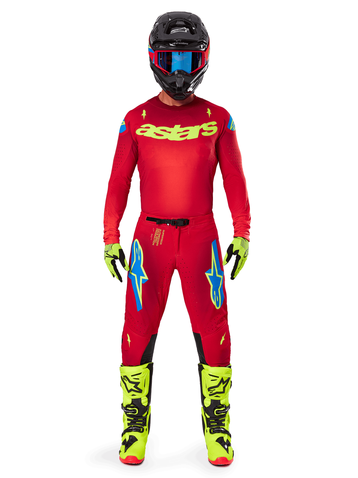 Piloto de motocross con el conjunto completo Alpinestars 2025 Supertech Maker, jersey rojo brillante con logotipo 'astars' en amarillo flúor, pantalones rojos a juego con detalles azules, casco negro con gafas azules, botas y guantes amarillo flúor, atuendo coordinado para competición off-road