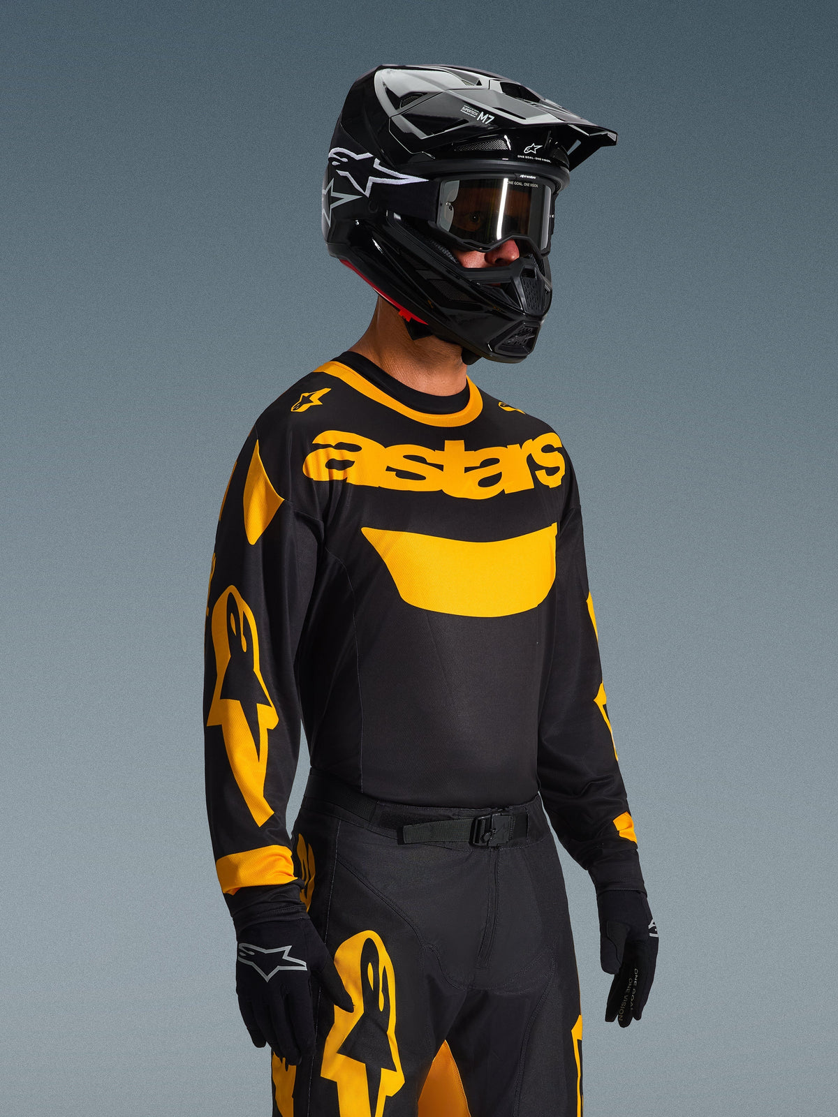 Conjunto Racer Riway 2026, piloto de motocross con jersey negro con la marca 'astars' y detalles amarillos en las mangas, pantalones negros y amarillos a juego, casco negro con gafas y guantes negros, equipamiento de competición off-road coordinado