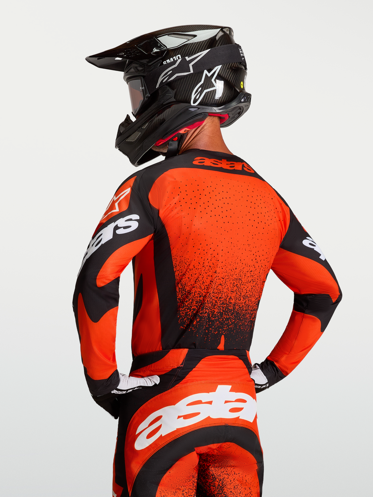 Alpinestars Jersey Techstar Swan, jersey de motocross para hombre, rojo cardenal y negro, ajuste atlético de carrera con ventilación láser, visto desde atrás en modelo con casco de MX