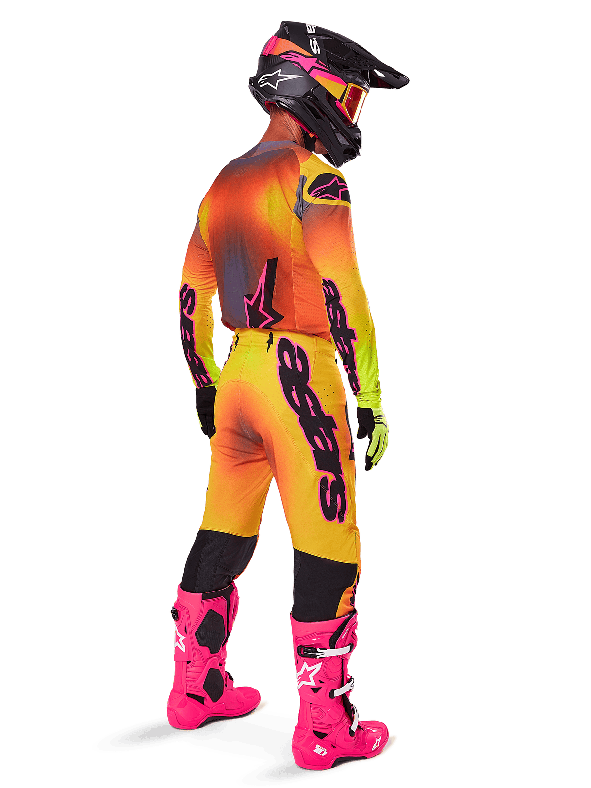Piloto de motocross desde atrás con el conjunto de equipo Alpinestars 2025 Supertech Lipan, jersey con degradado amarillo y naranja con detalles rosas, pantalones a juego, botas rosa brillante y casco negro con gráficos en rosa y amarillo, atuendo coordinado para carreras profesionales