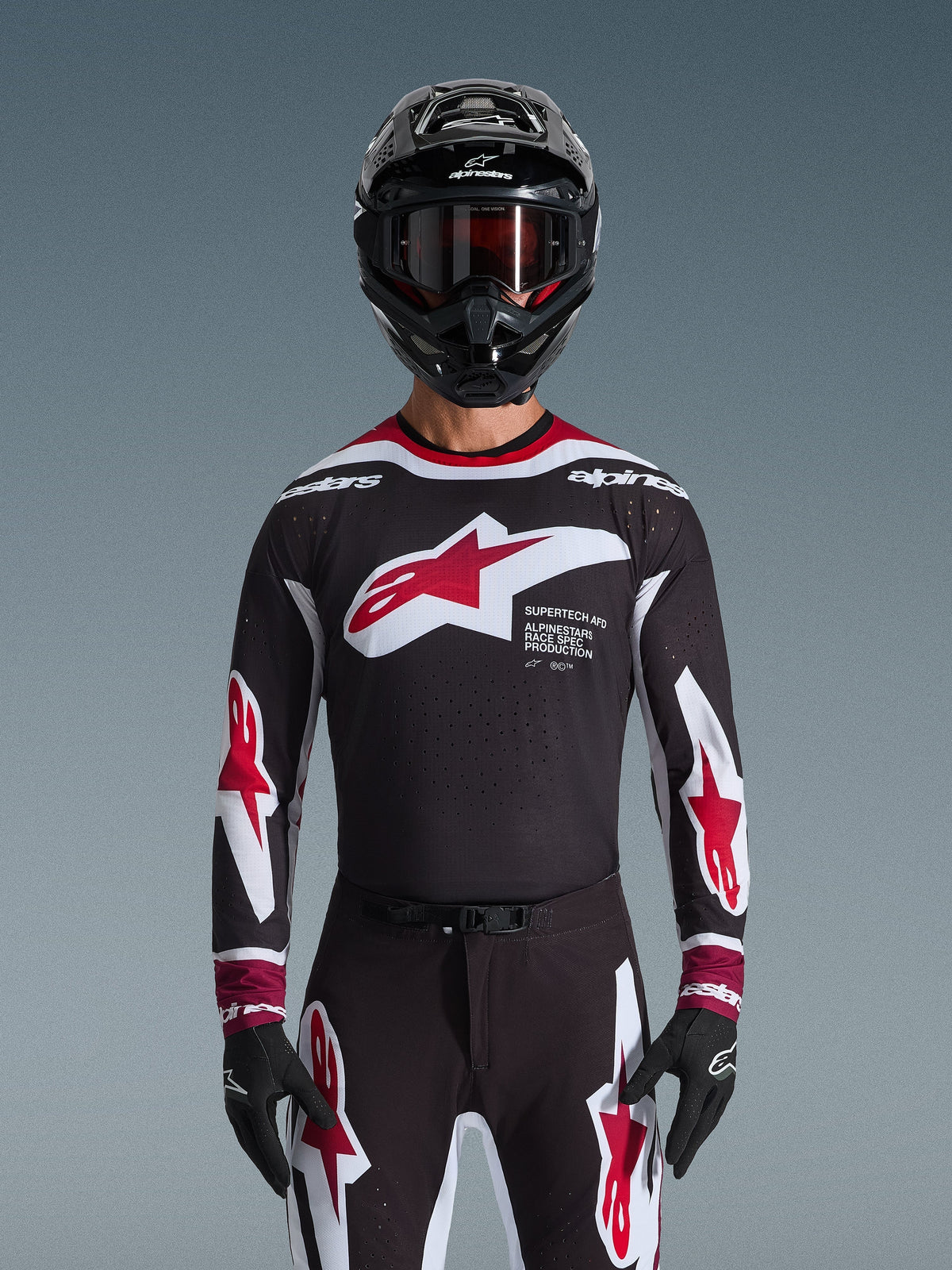 Alpinestars 2026 Supertech AFD Vista Jersey, Motocross Jersey in Black Red and White, shown on a rider with a black helmet, goggles, and gloves, featuring a large chest logo and 'SUPERTECH AFD' branding, professional racing gear for off-road performance