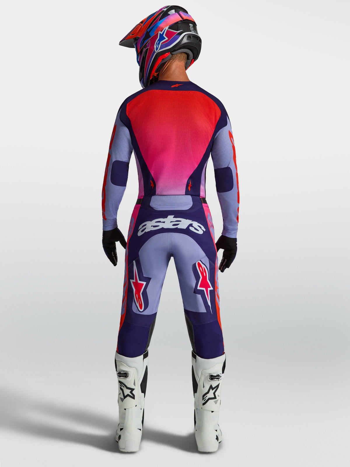 Alpinestars Racer Air Hunt JGear Set, conjunto de motocross ventilado, morado y rojo, vista trasera del piloto con casco y botas.