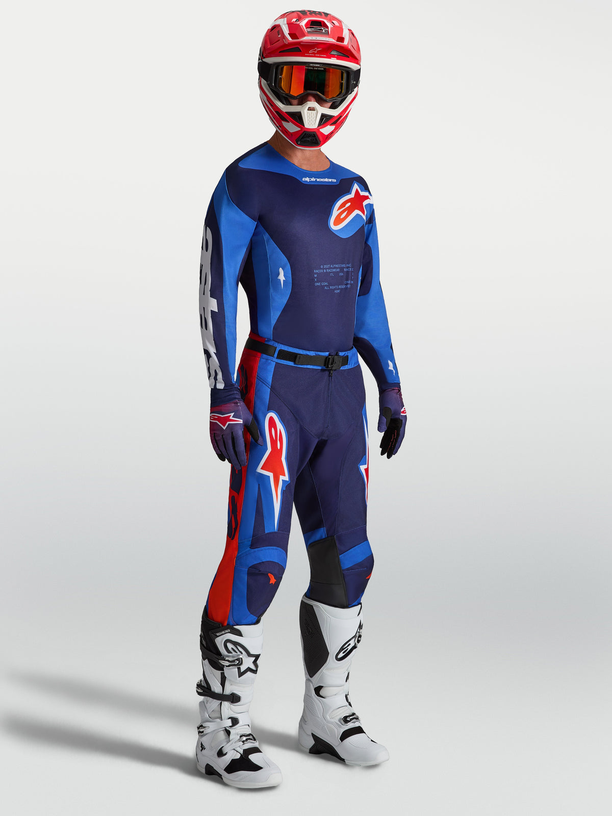 Alpinestars Racer Hunt Gear Set, conjunto de motocross azul marino y azul con detalles rojos, botas blancas y casco rojo.