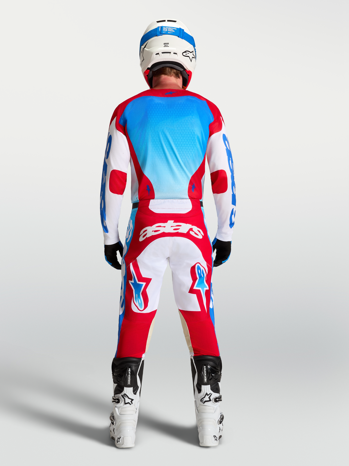 Alpinestars Pantalones Racer Hunt y Racer Hunt Gear Set, equipo de motocross rojo, blanco y azul, vista trasera en modelo con casco y botas